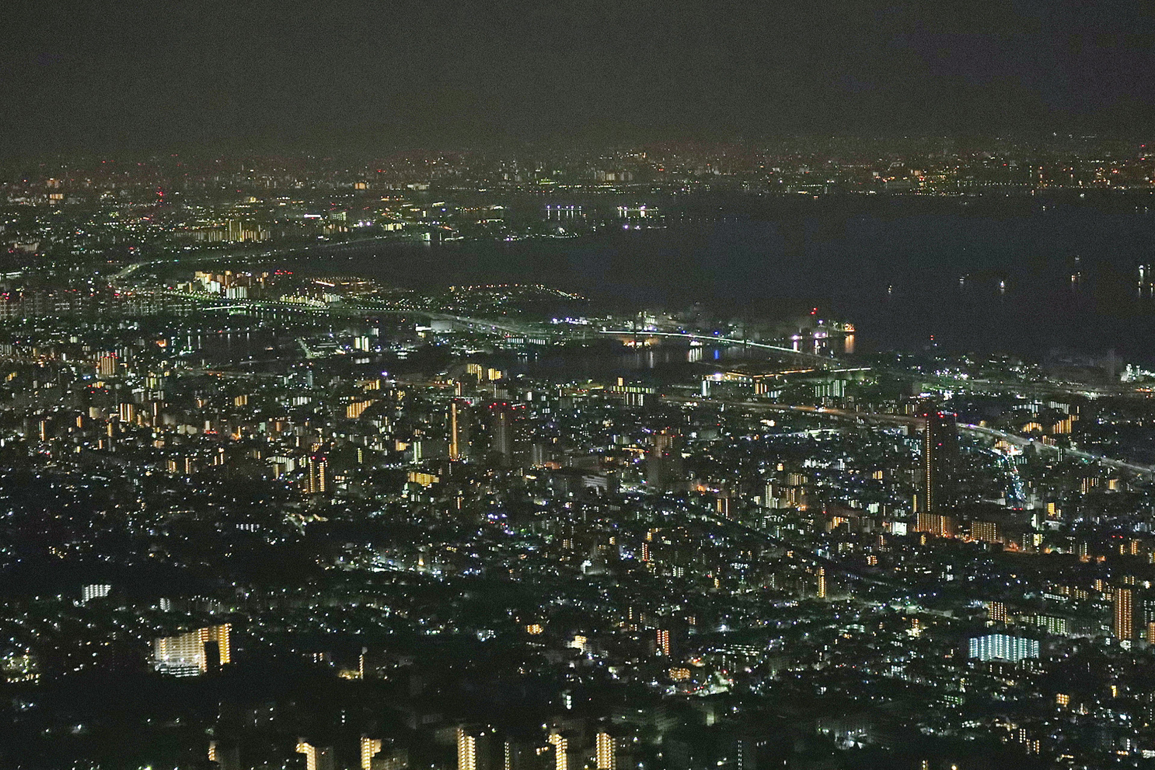 Vista nocturna de un paisaje urbano con edificios iluminados y frente marítimo