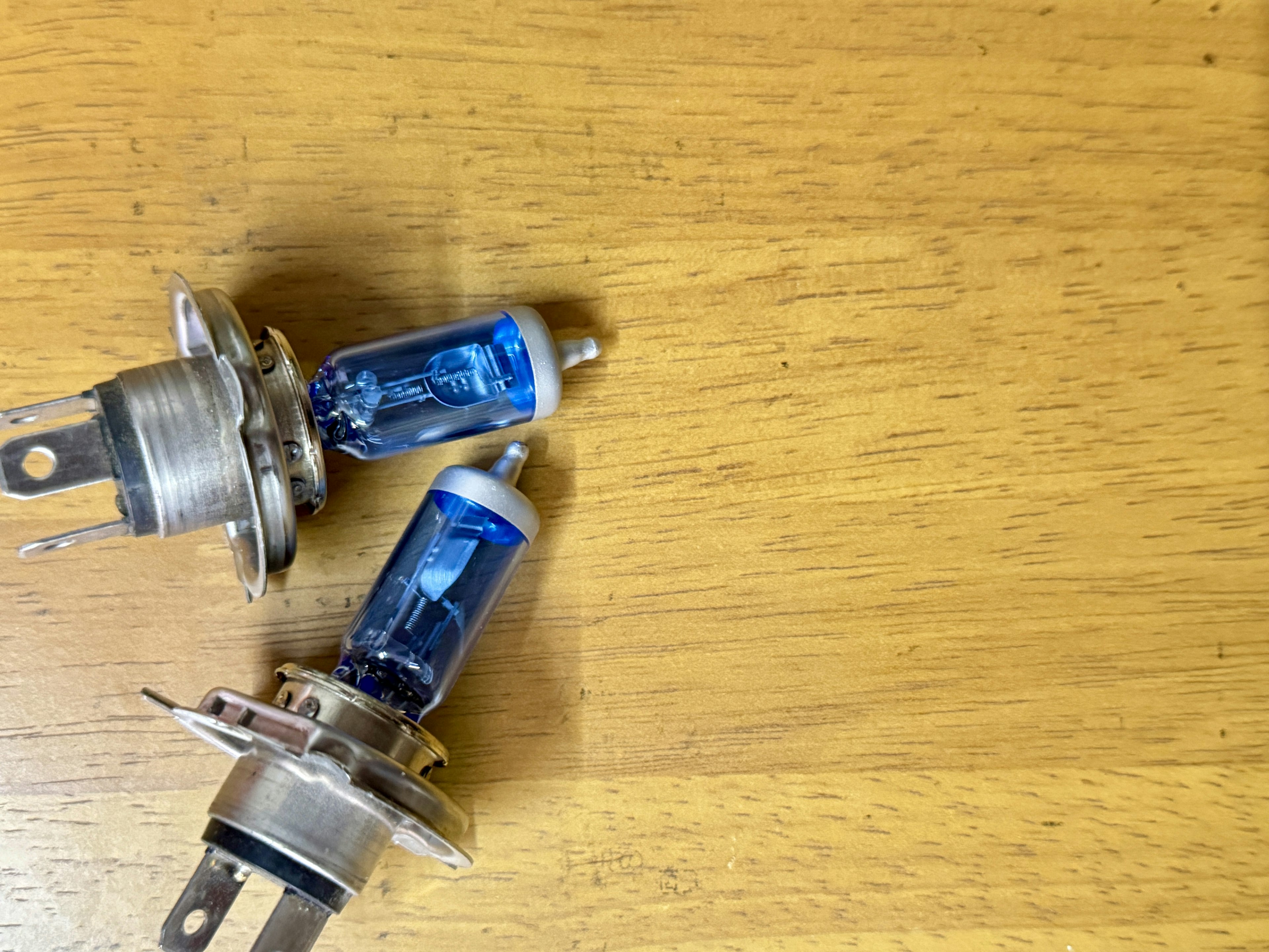 Two blue halogen bulbs resting on a wooden surface