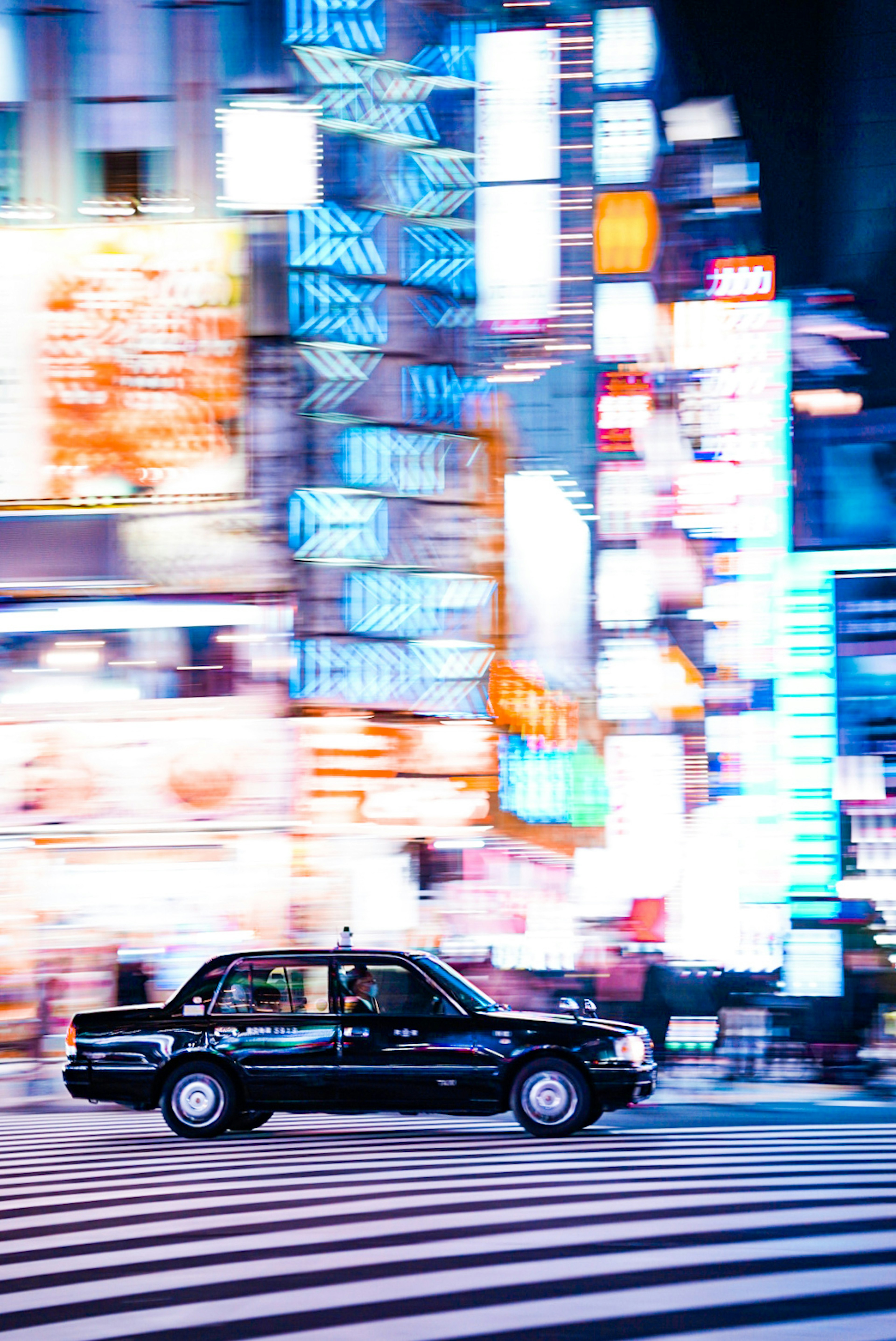 Taxi nero che attraversa una vivace strada di Tokyo con luci al neon