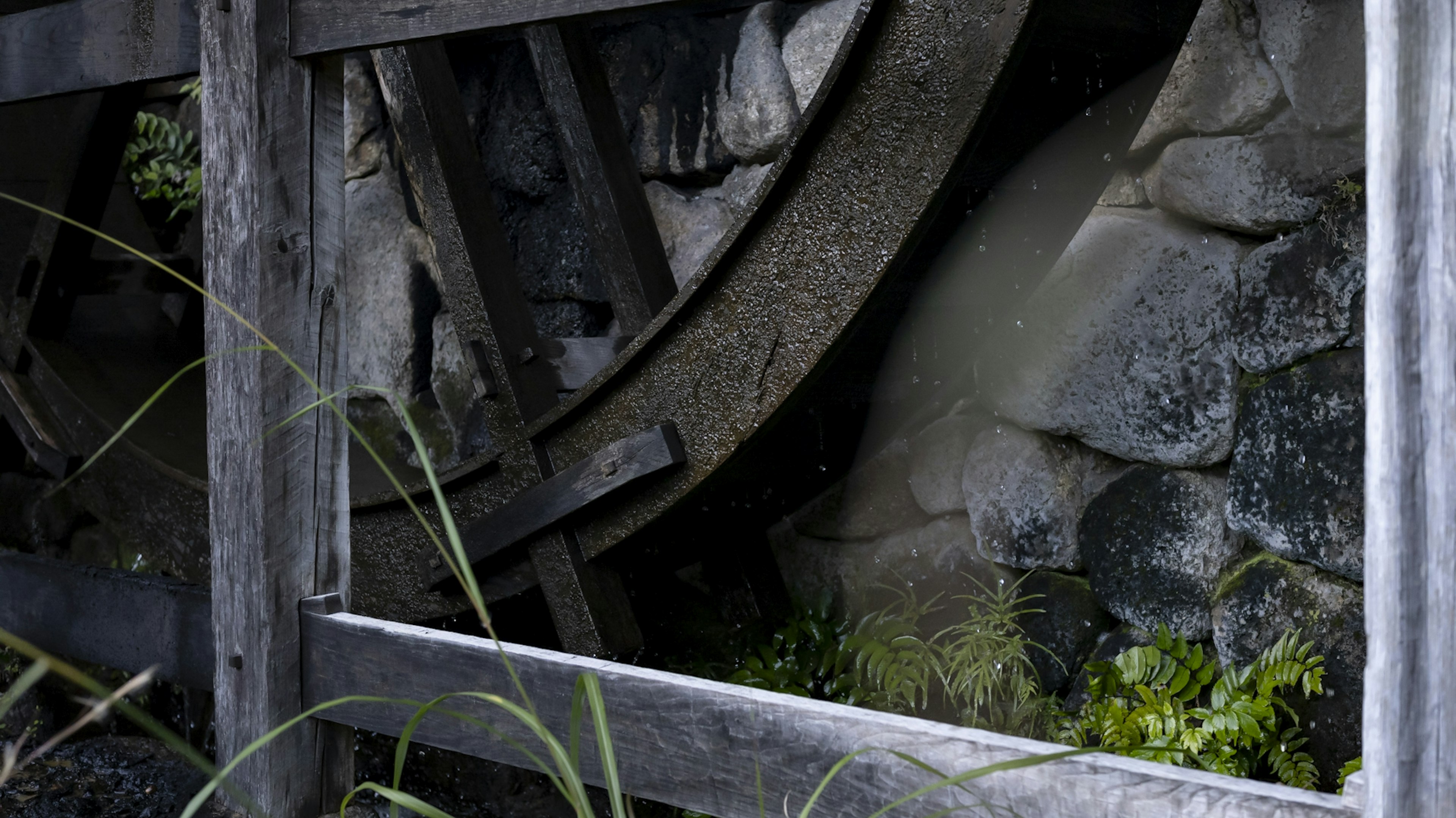 A section of an old water wheel visible through a wooden frame