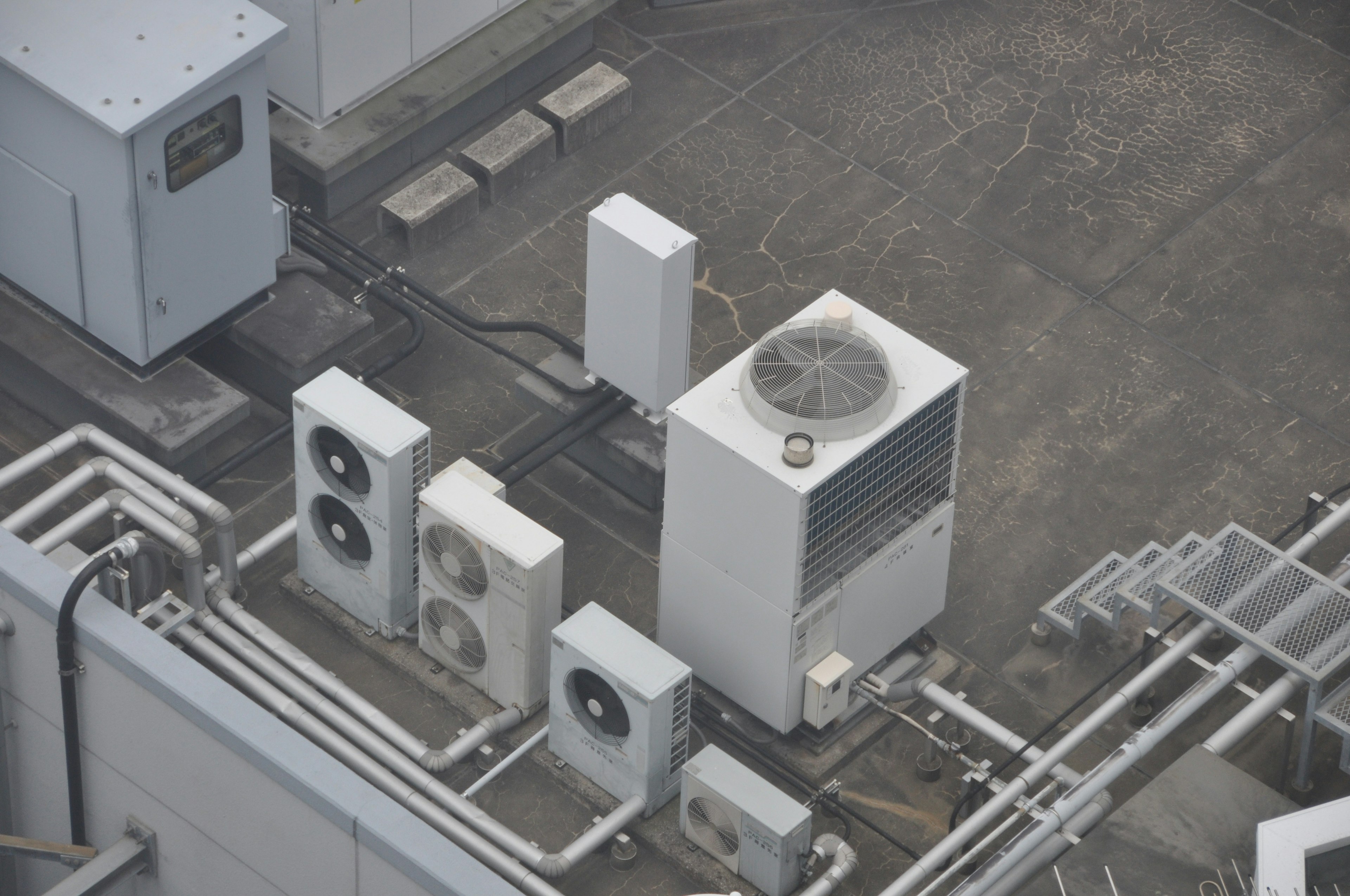 Array of air conditioning units and pipes on a rooftop