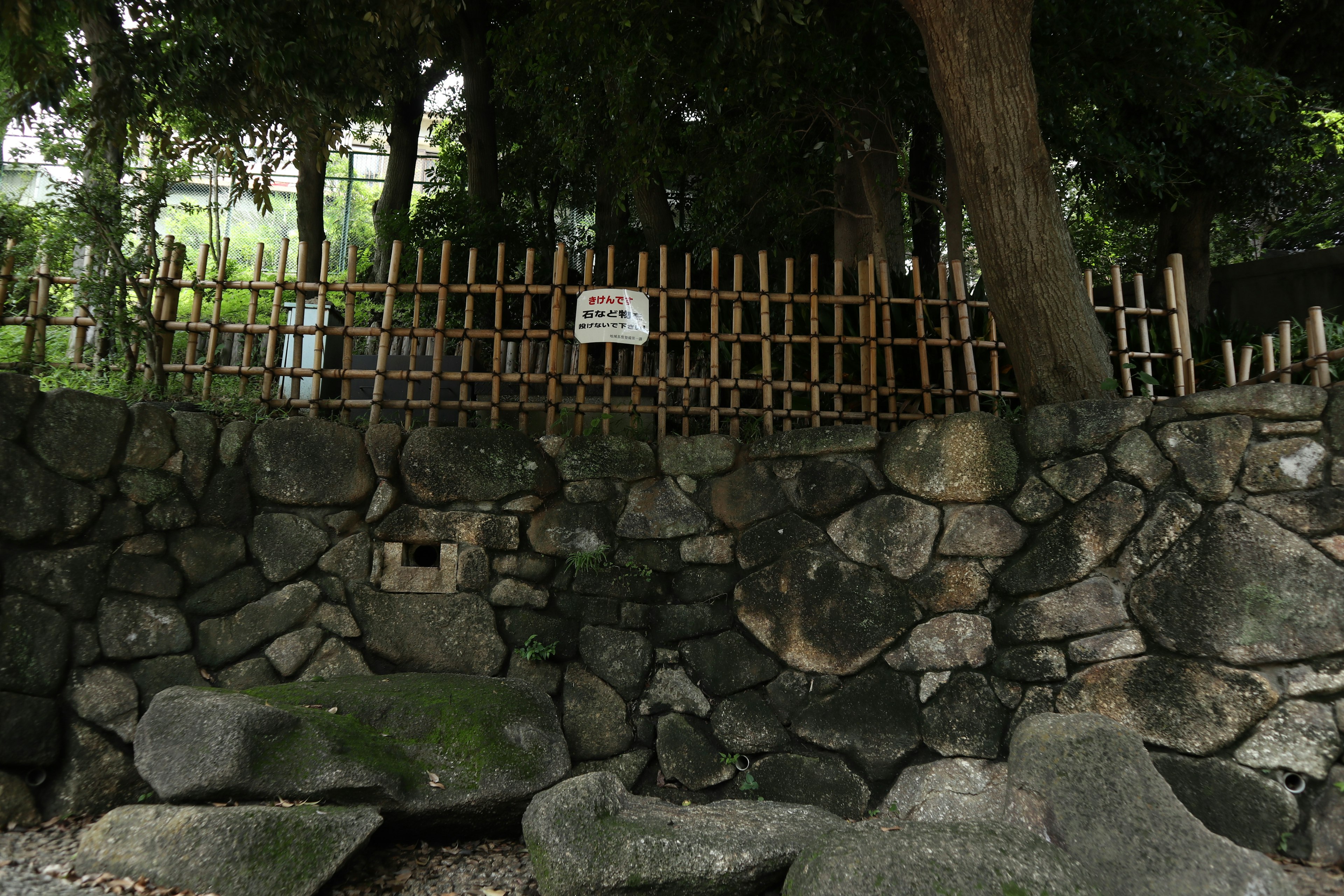 石造りの壁と竹のフェンスがある緑豊かな風景