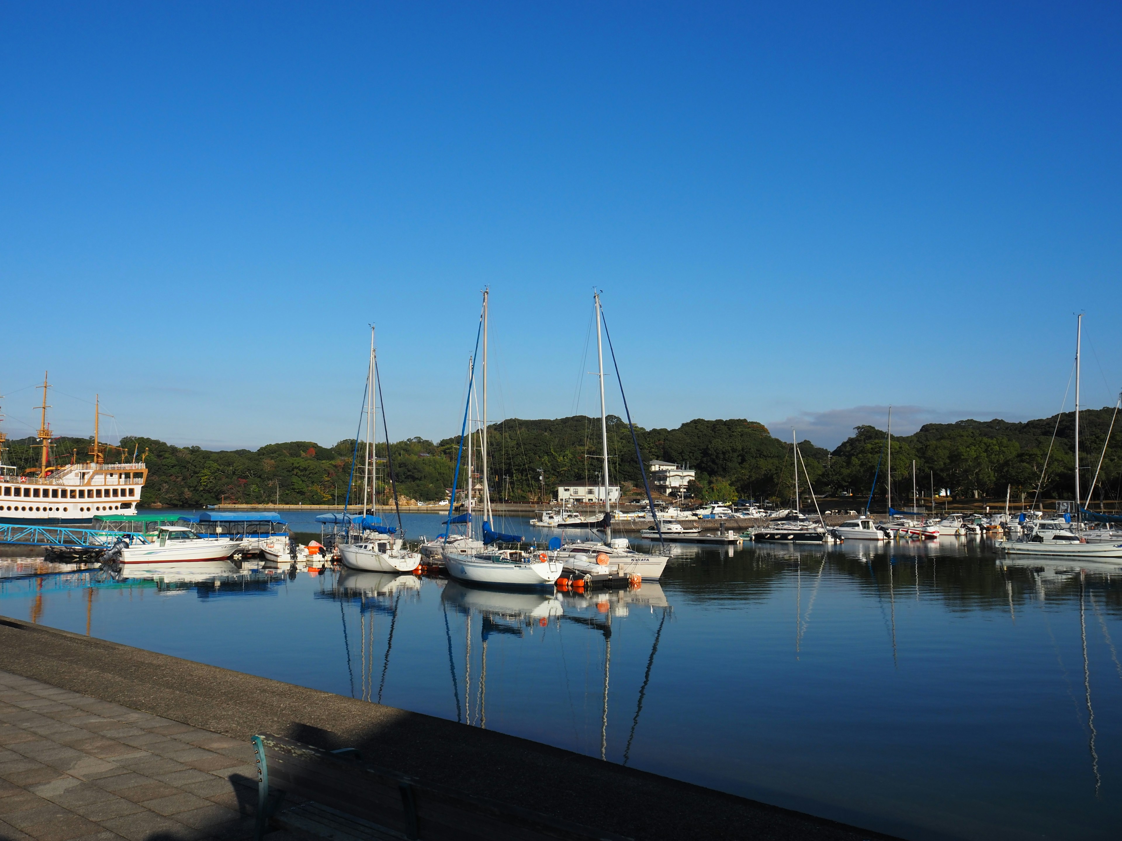 Hafenszene mit mehreren Yachten und Booten, die unter einem klaren blauen Himmel liegen