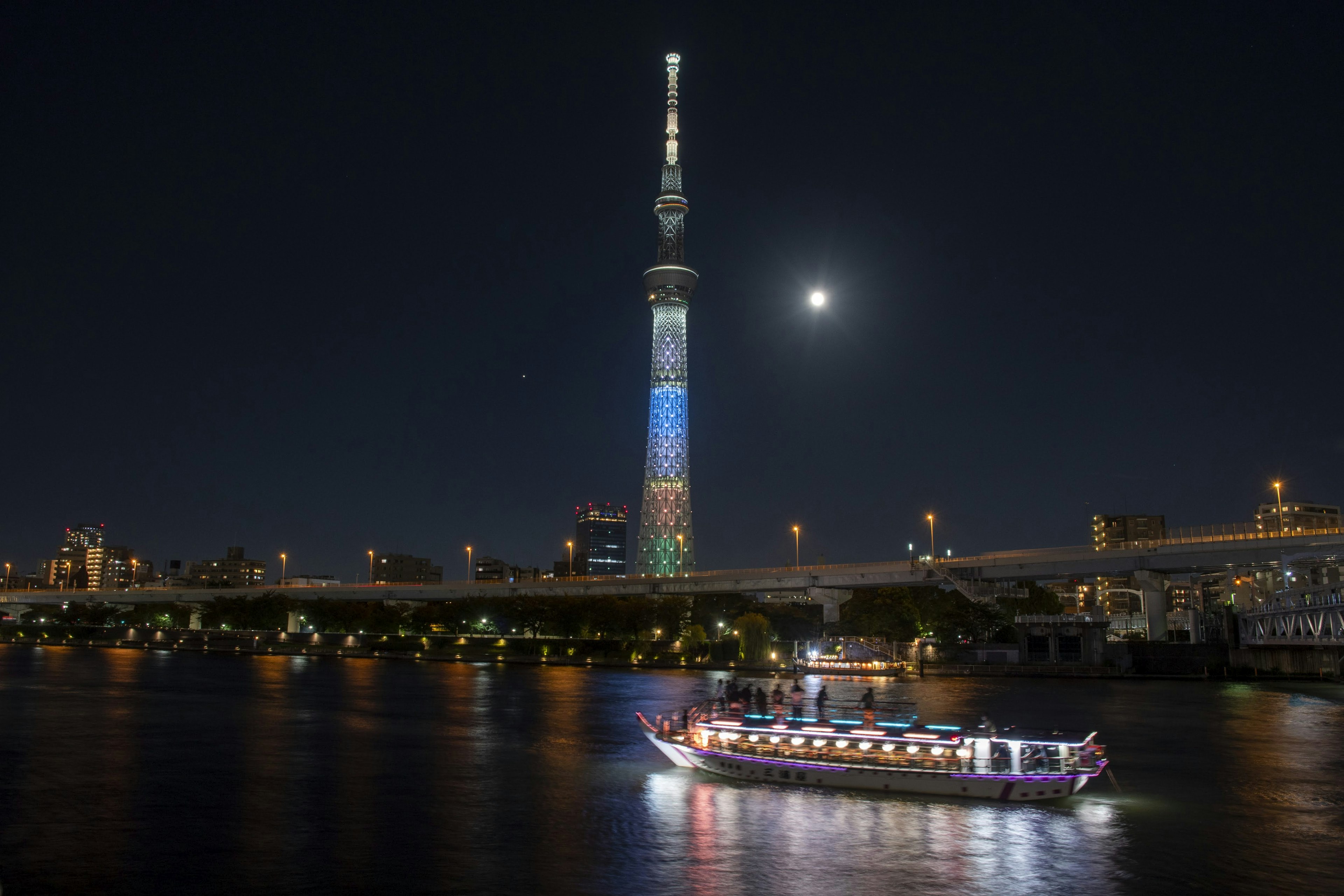 Tokyo Skytree được chiếu sáng vào ban đêm với một chiếc thuyền trên sông