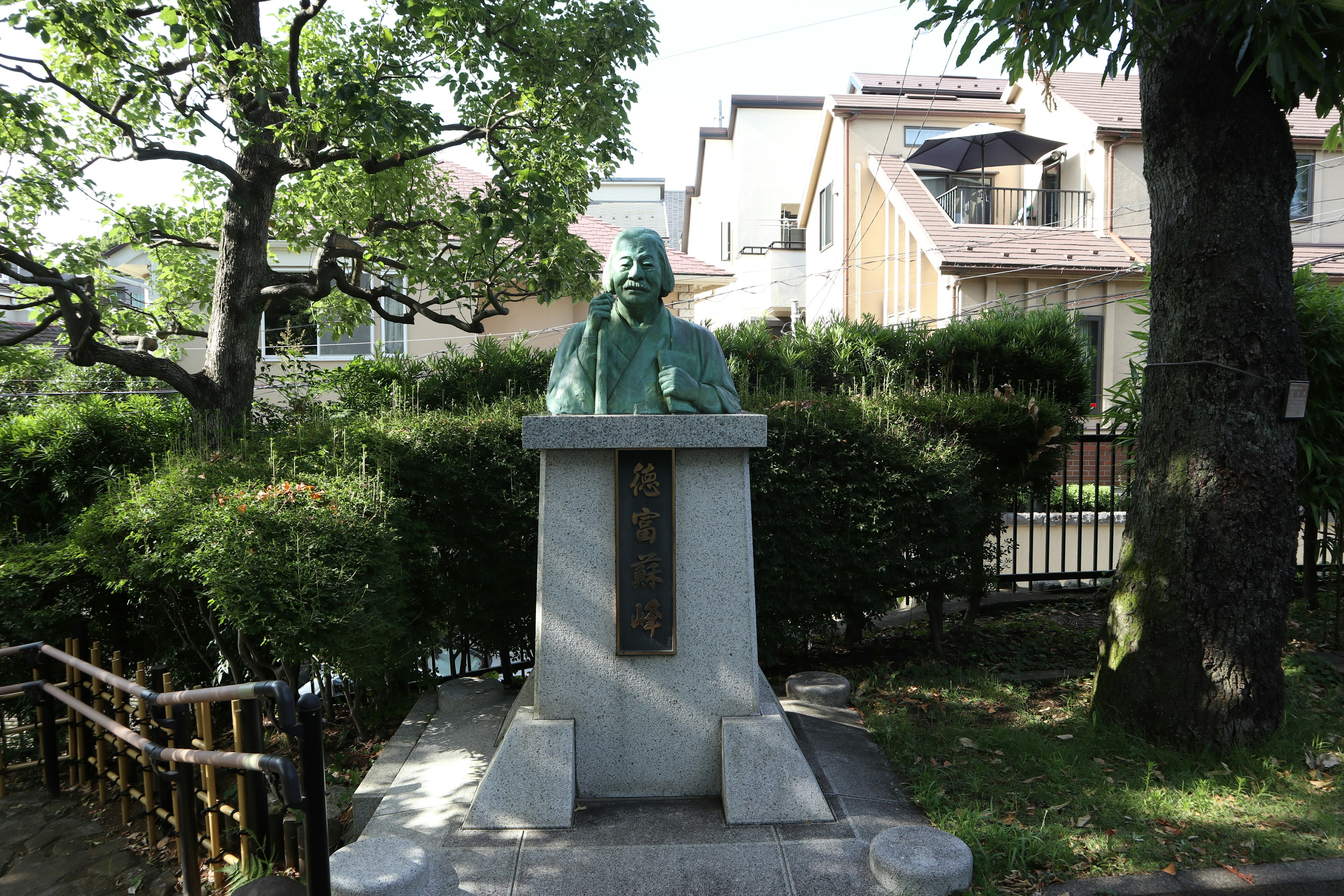 Estatua de bronce en un jardín verde con casas alrededor