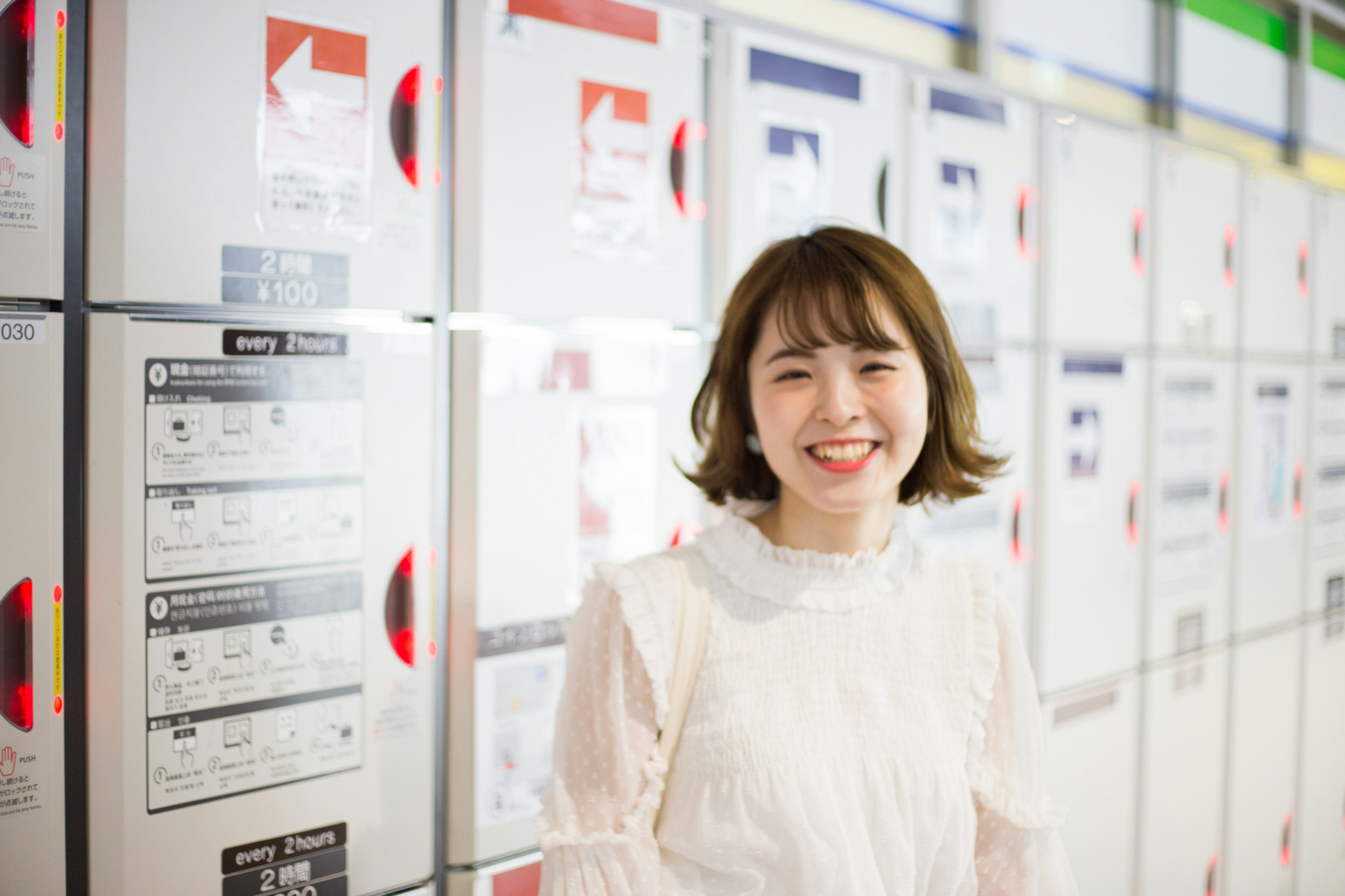 Smiling woman in front of lockers wearing a white blouse