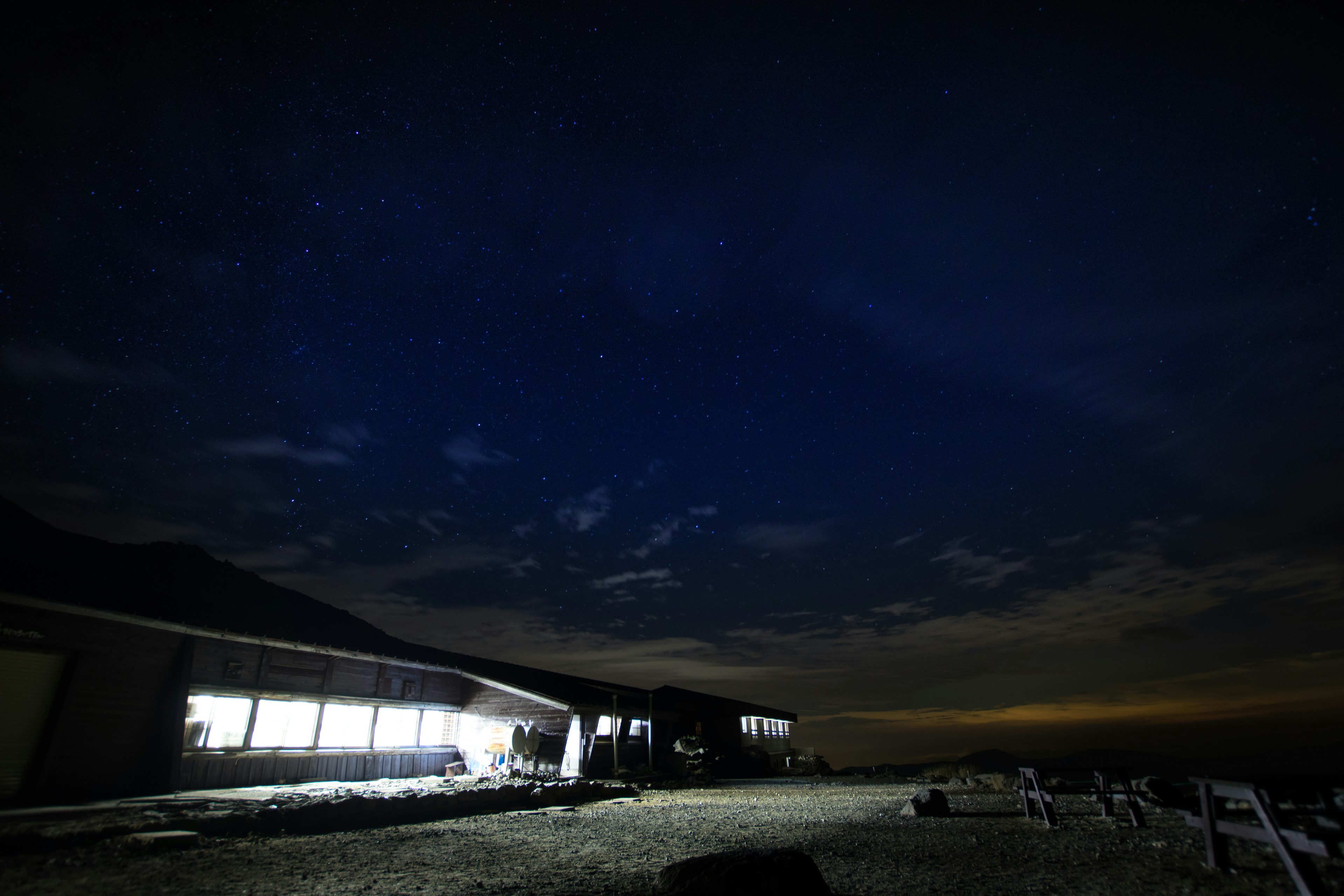 Cielo nocturno con estrellas visibles y un edificio iluminado