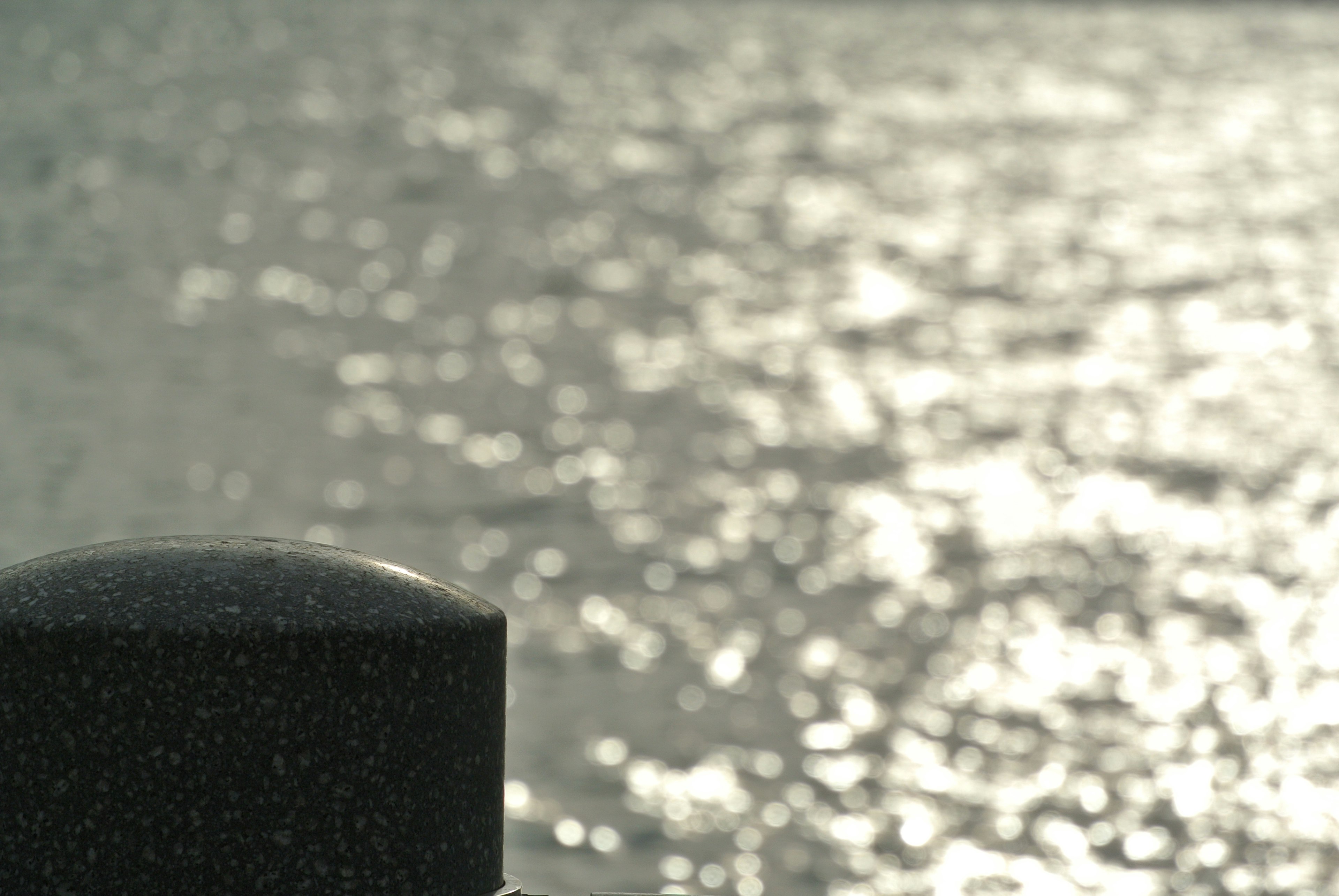 Close-up shot of a black post with a shiny water surface in the background