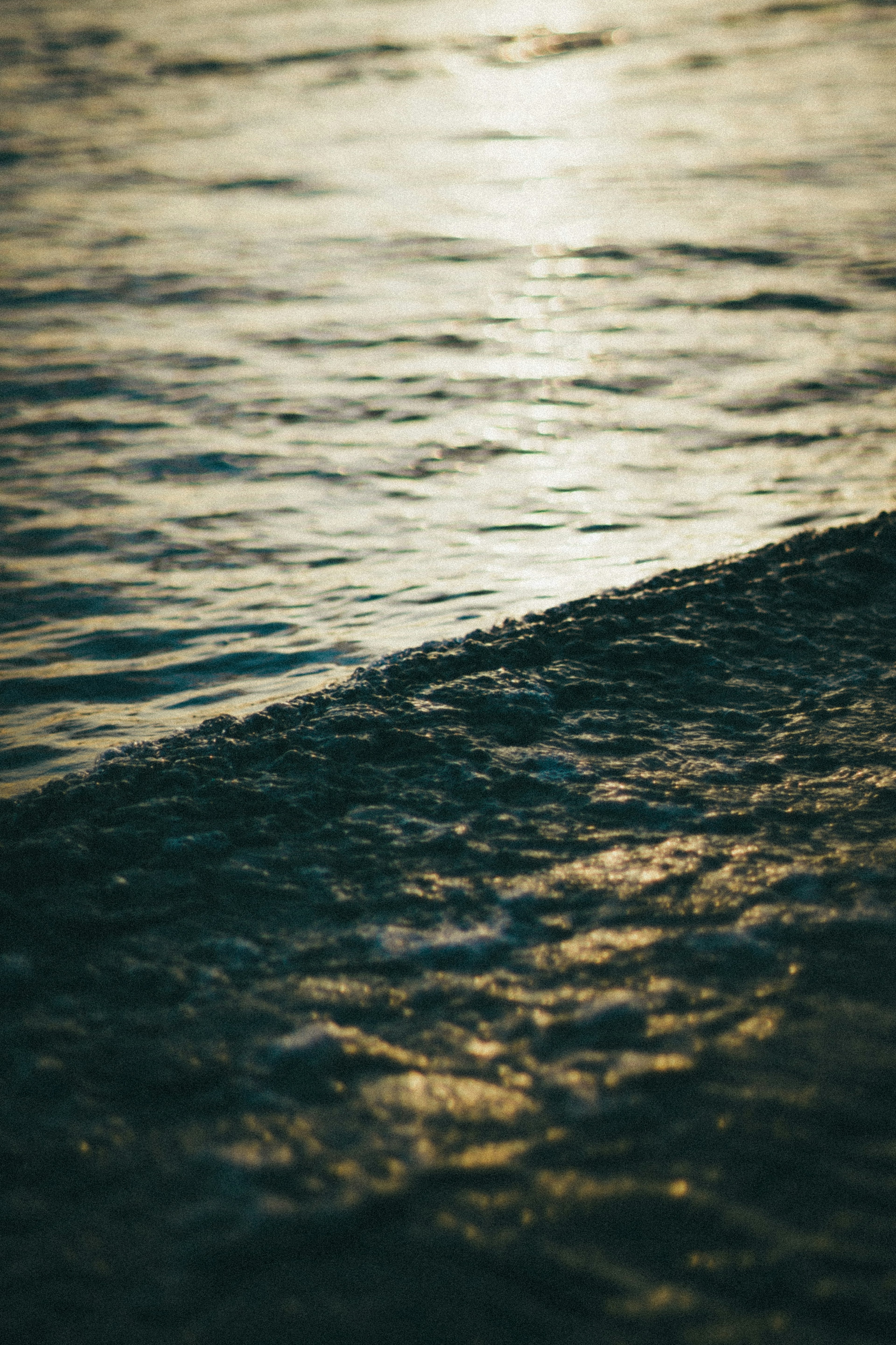 Nahaufnahme der welligen Wasseroberfläche mit sanftem Abendlicht