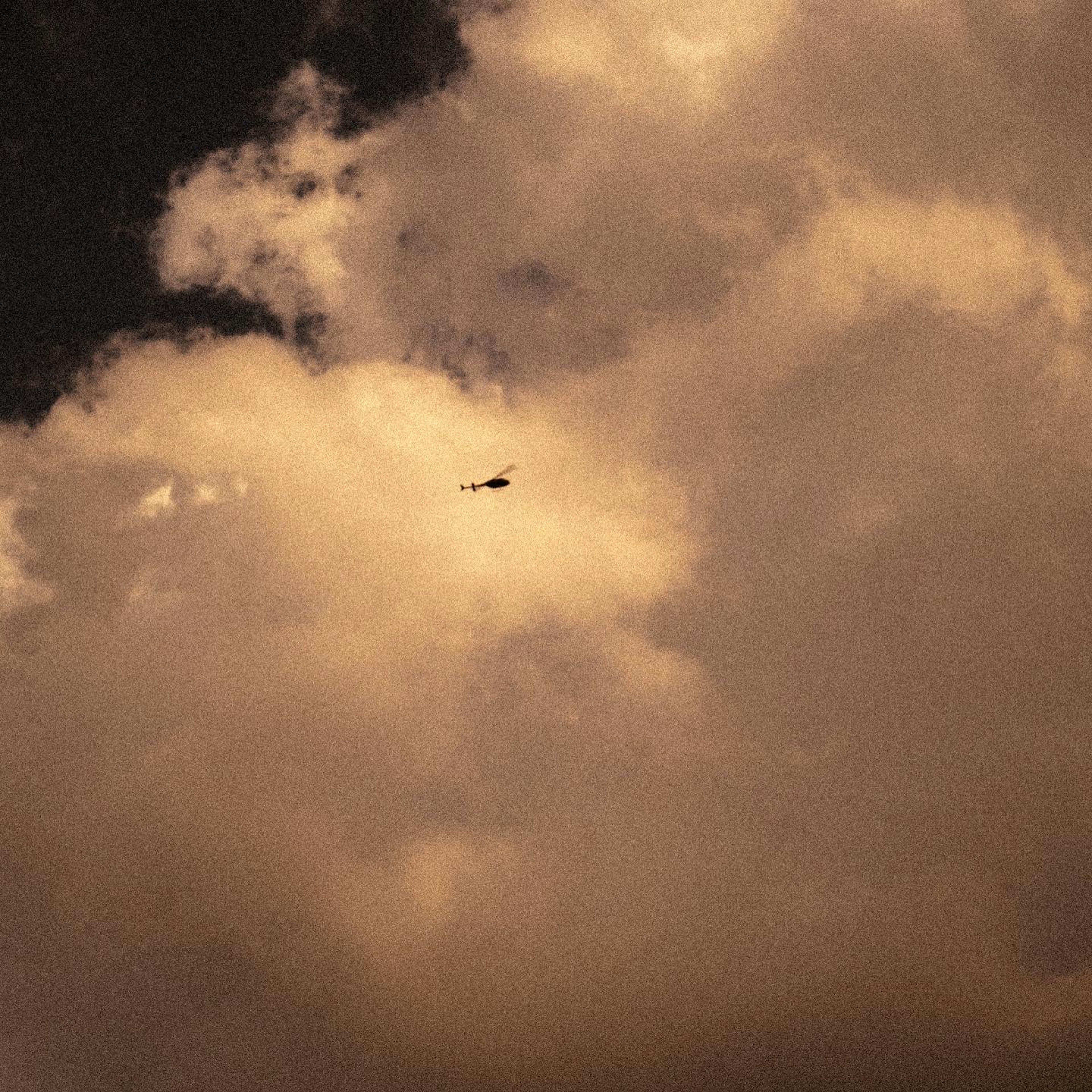 雲の間を飛ぶ小さな飛行機と暗い雲