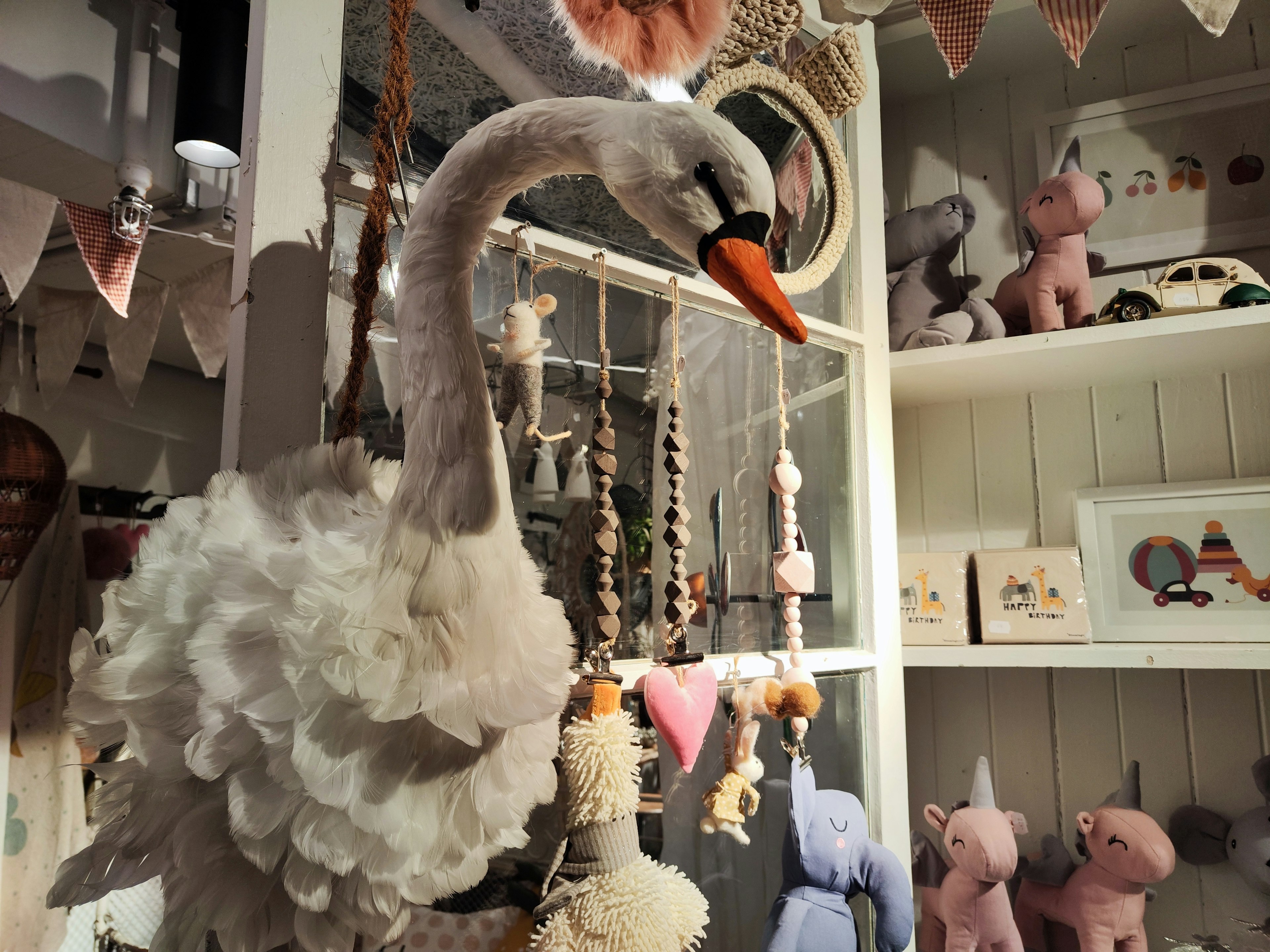 Cigno di peluche decorativo appeso in una stanza con vari giocattoli