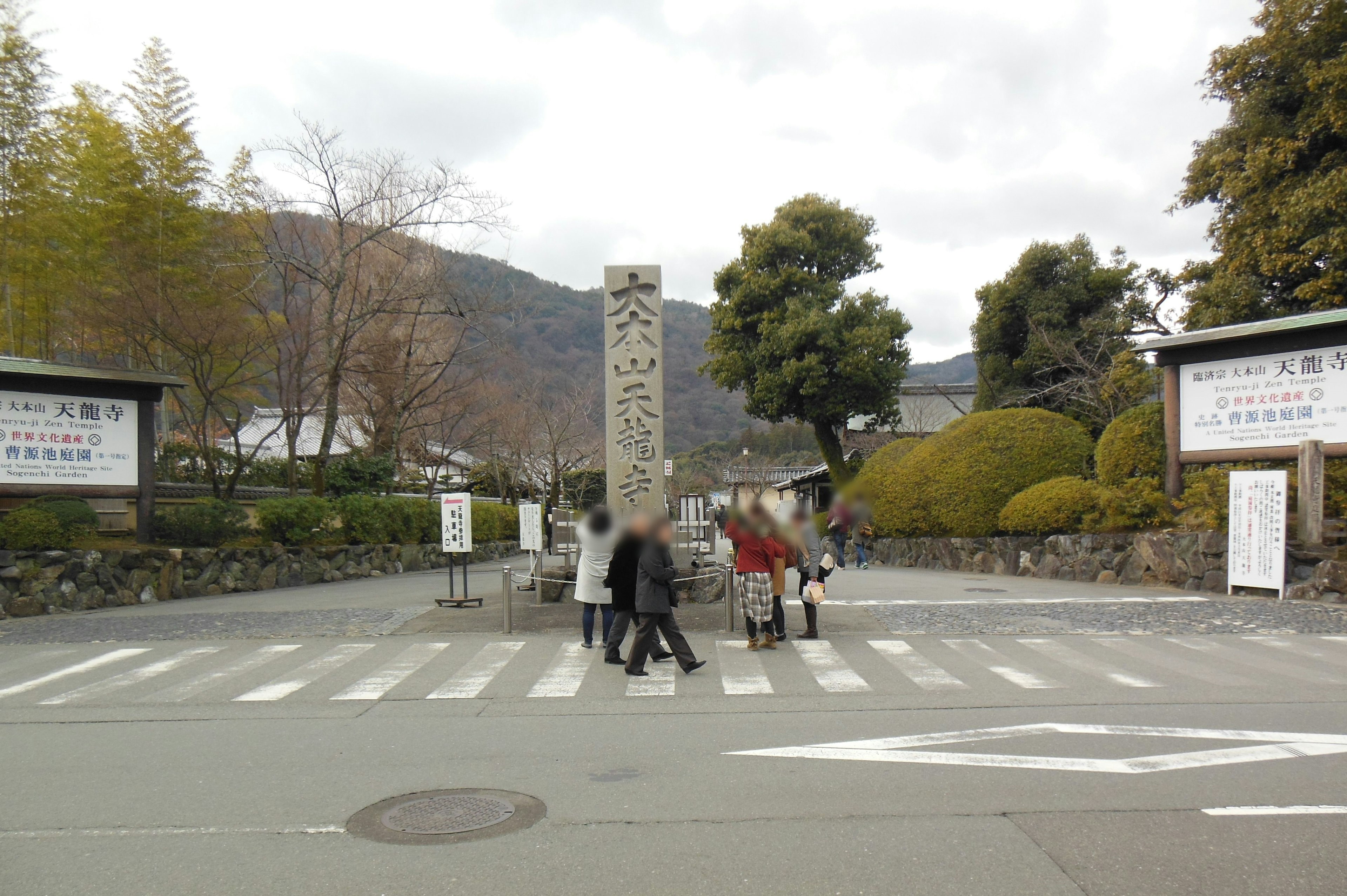 Escena de personas cruzando un paso peatonal con un monumento de piedra