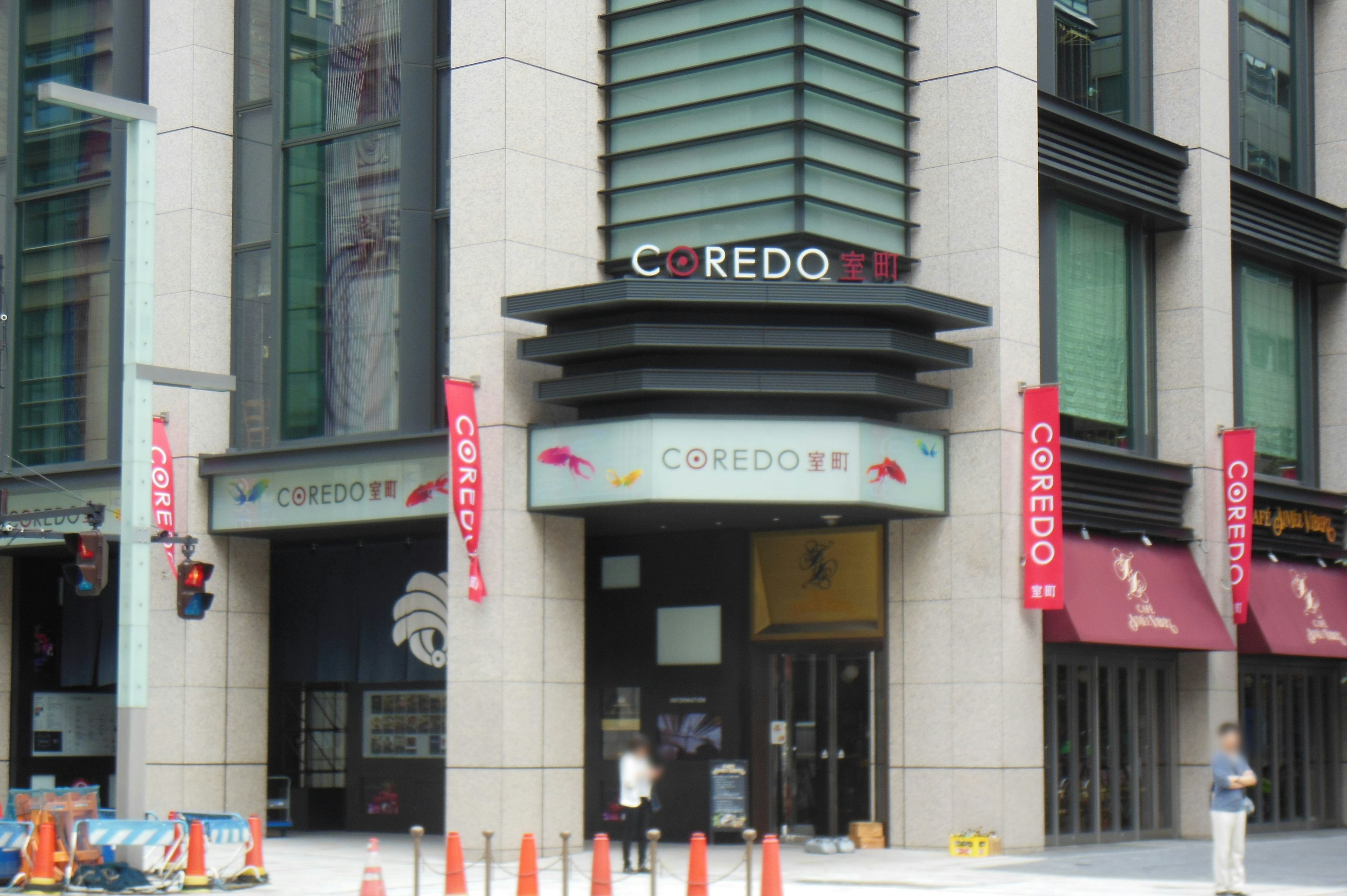 ภายนอกของ COREDO Nihonbashi มีป้ายสีแดงหลายป้ายและสัญญาณจราจรที่มองเห็นได้