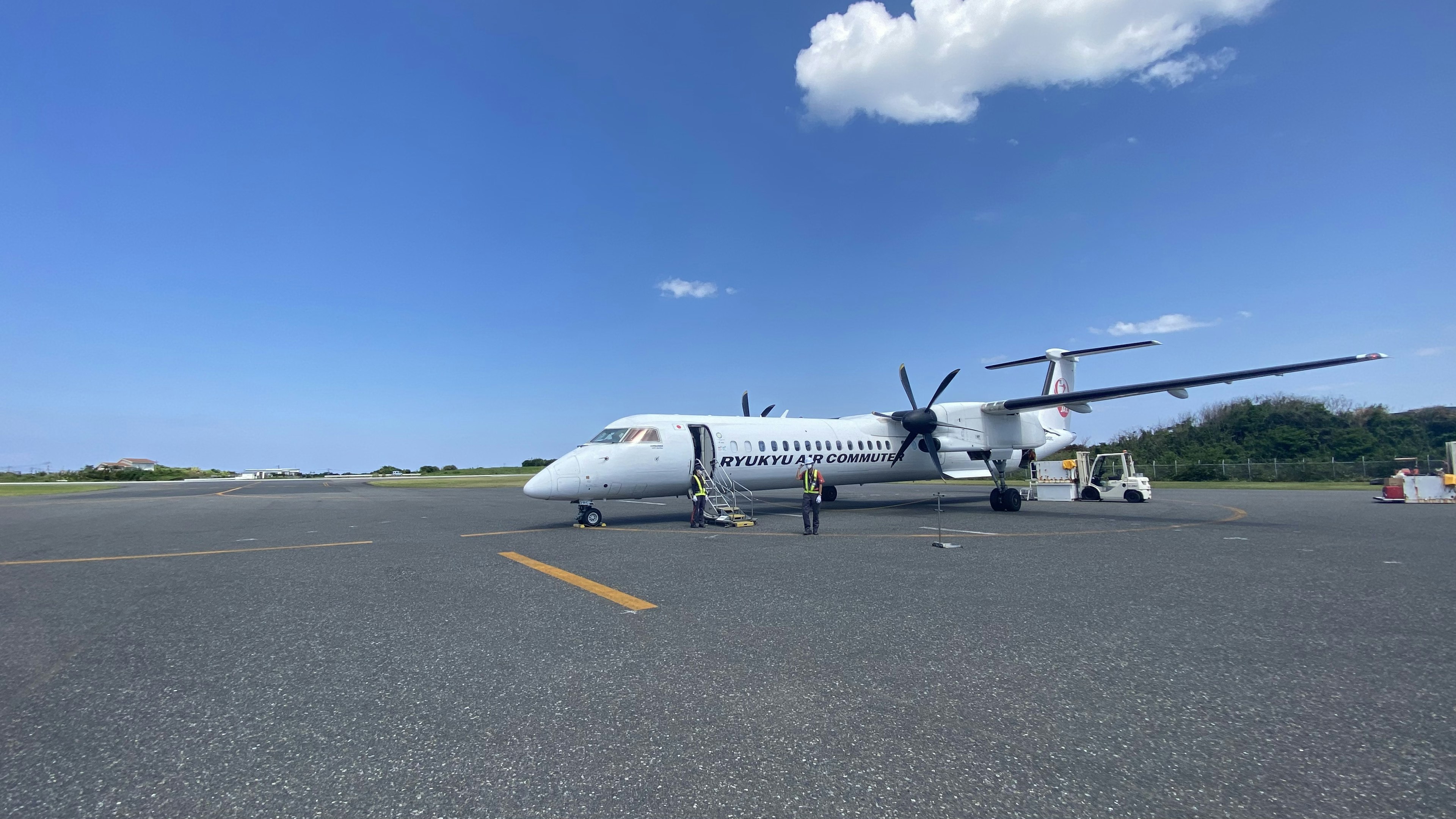 White turboprop airplane parked on the runway under a blue sky