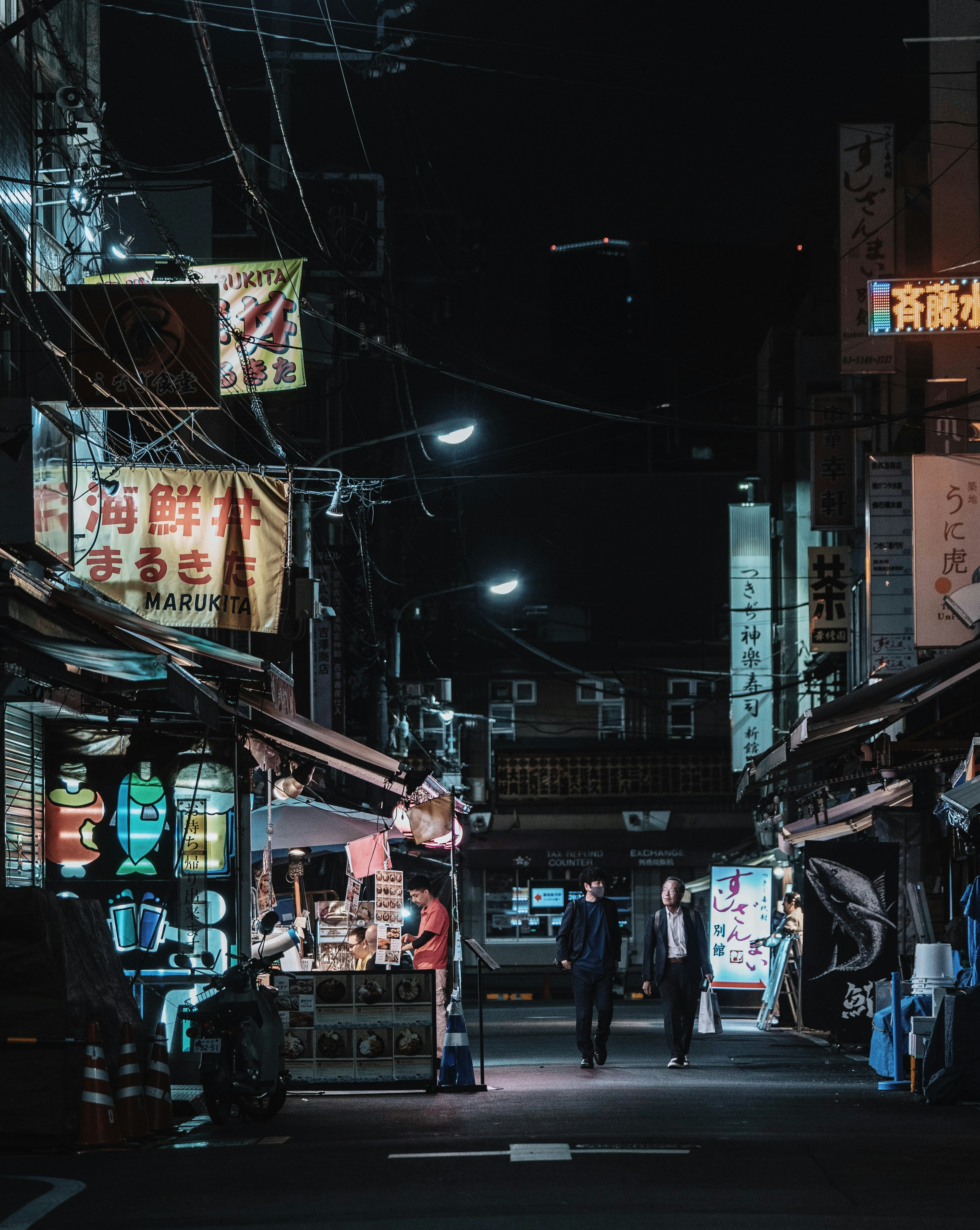 夜の市場通りに立つ人々とネオン看板のある風景