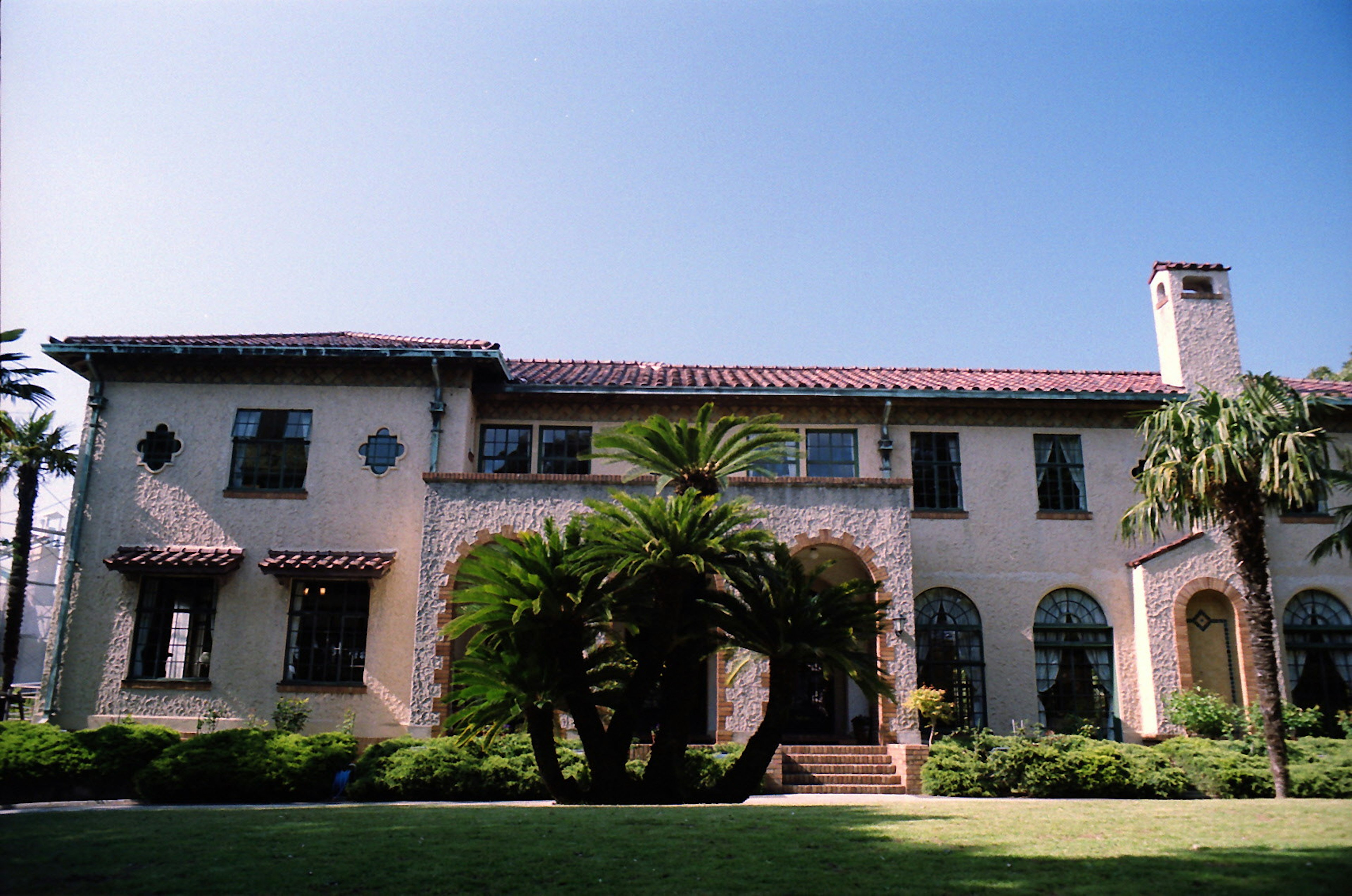 Exterior elegante de mansión con cielo azul jardín verde palmeras arquitectura histórica