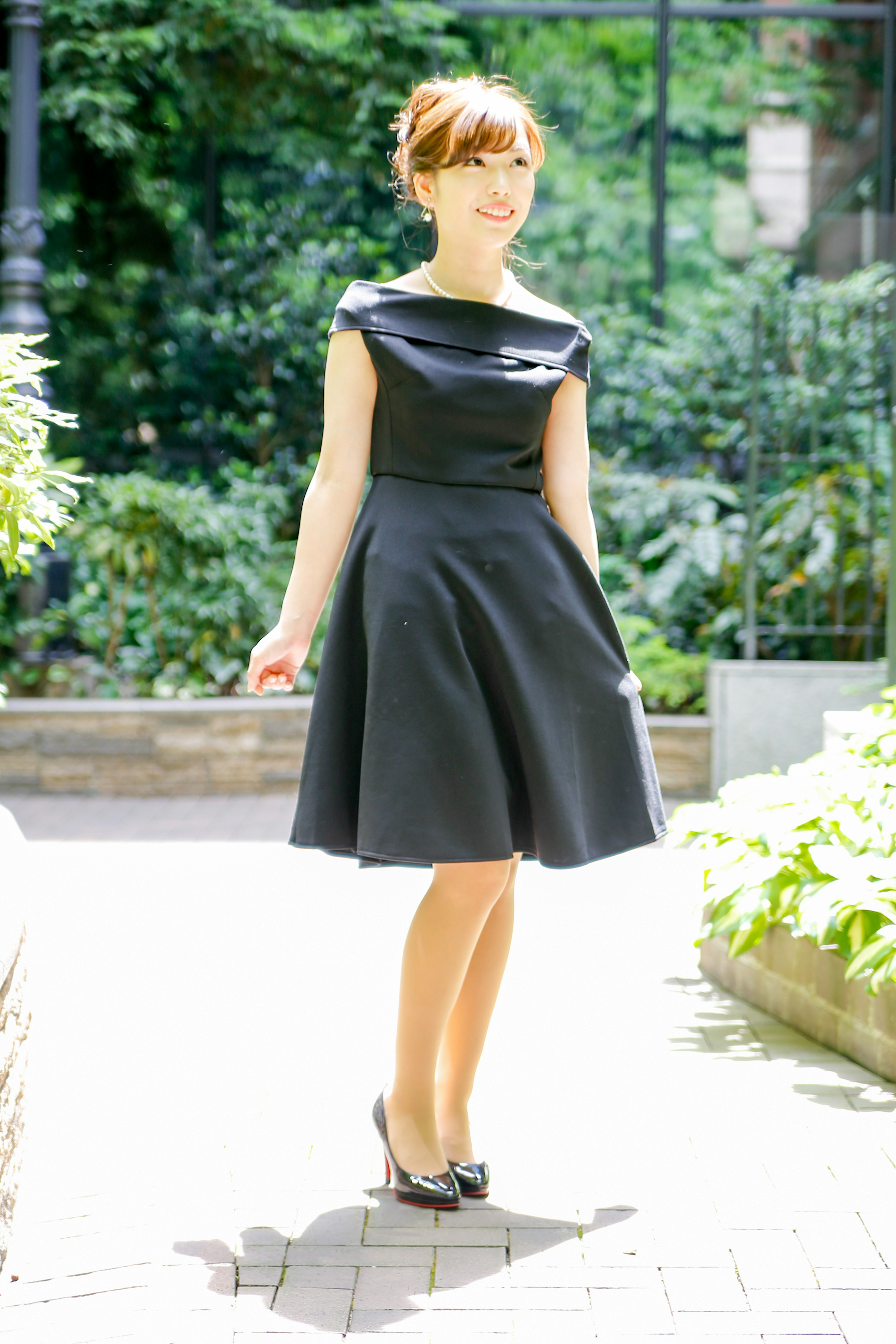 Une femme en robe noire posant dans un jardin