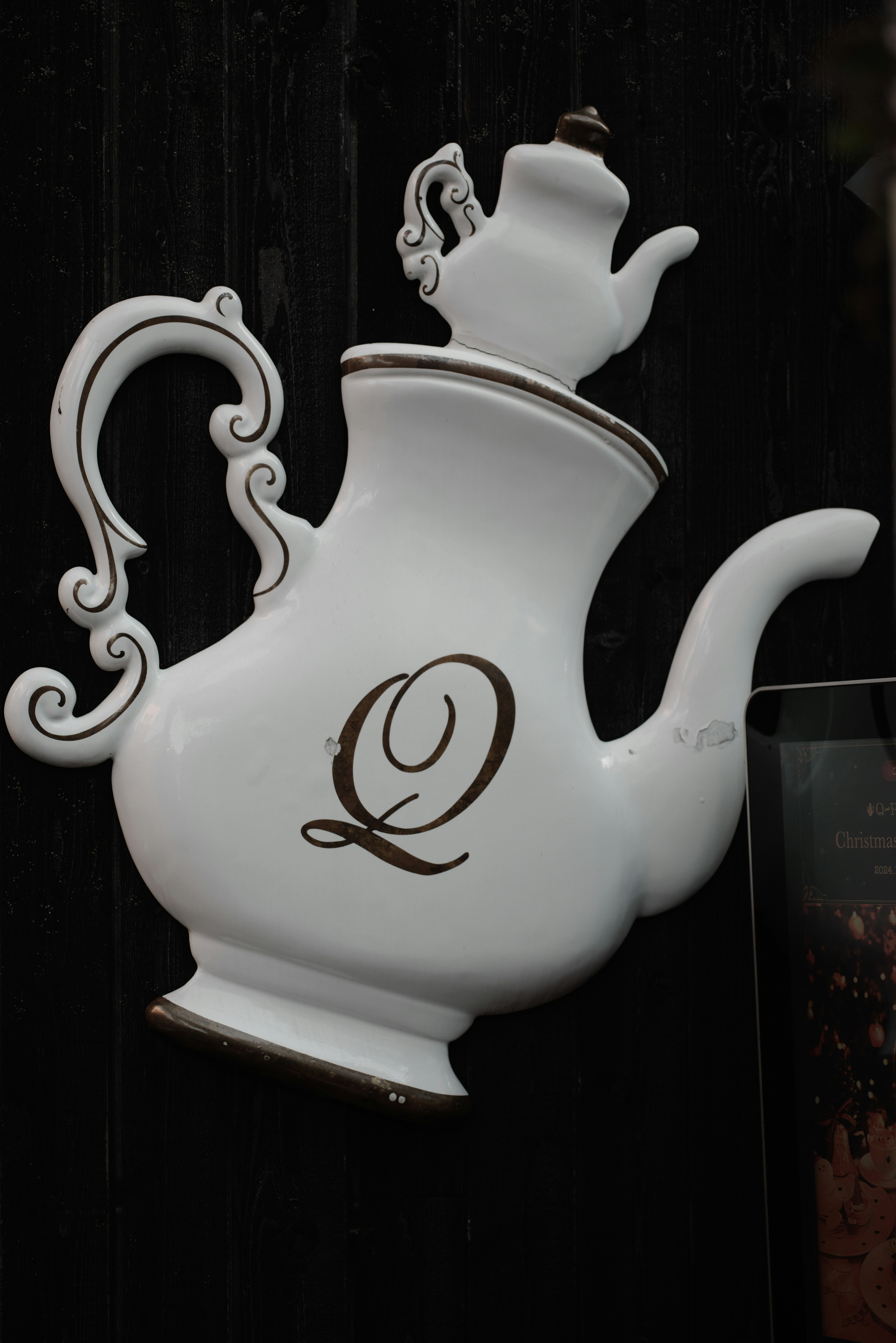 White teapot with gold accents and a letter Q design