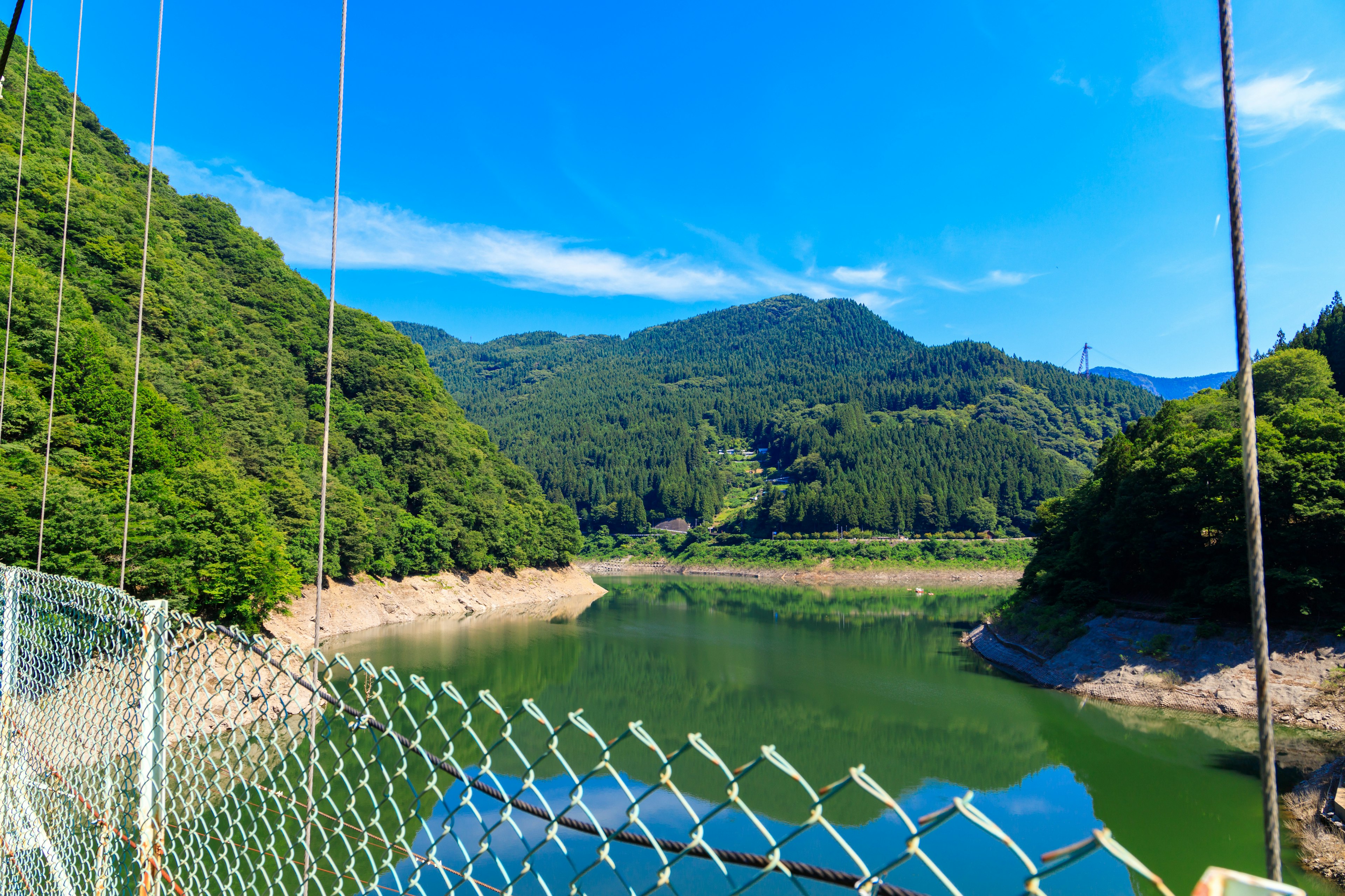 青空の下の山々と湖の景色 橋のケーブルが映る