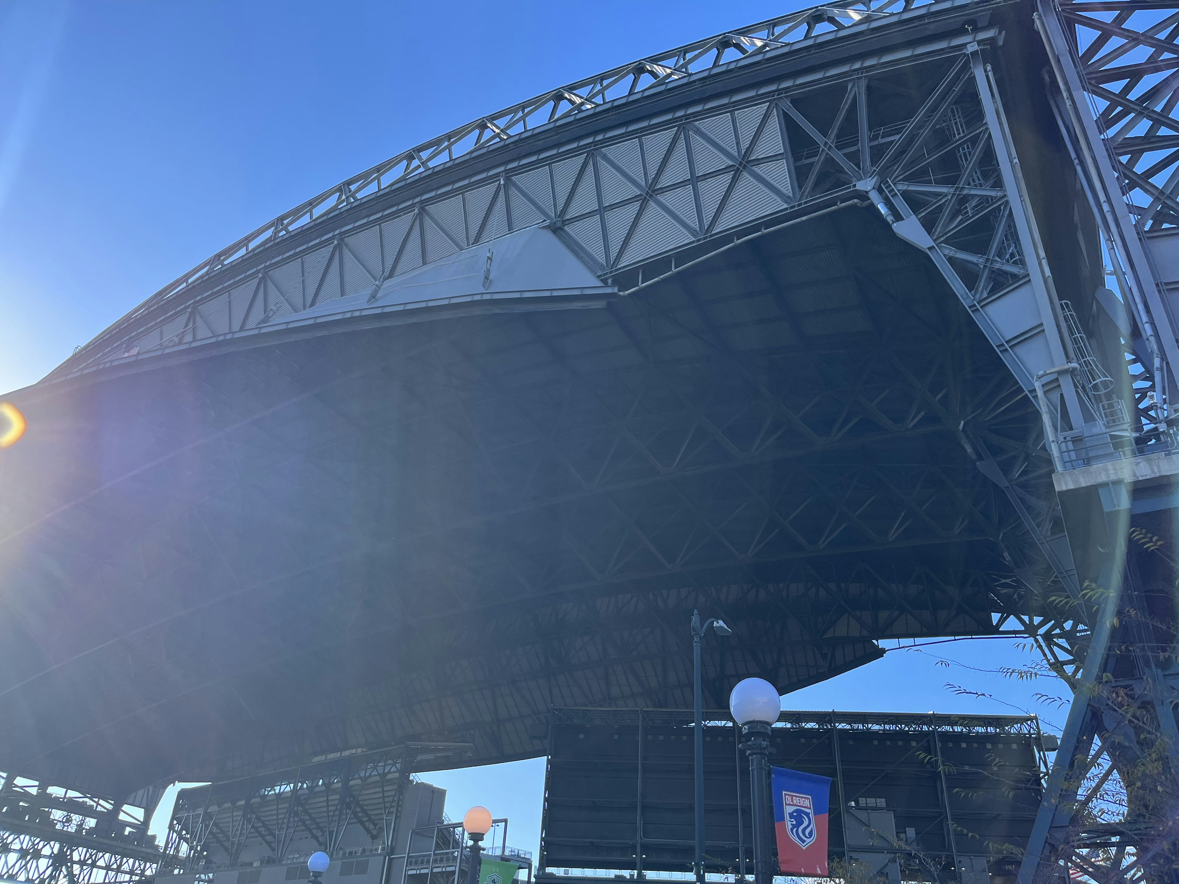 View from underneath a stadium roof showing a clear blue sky