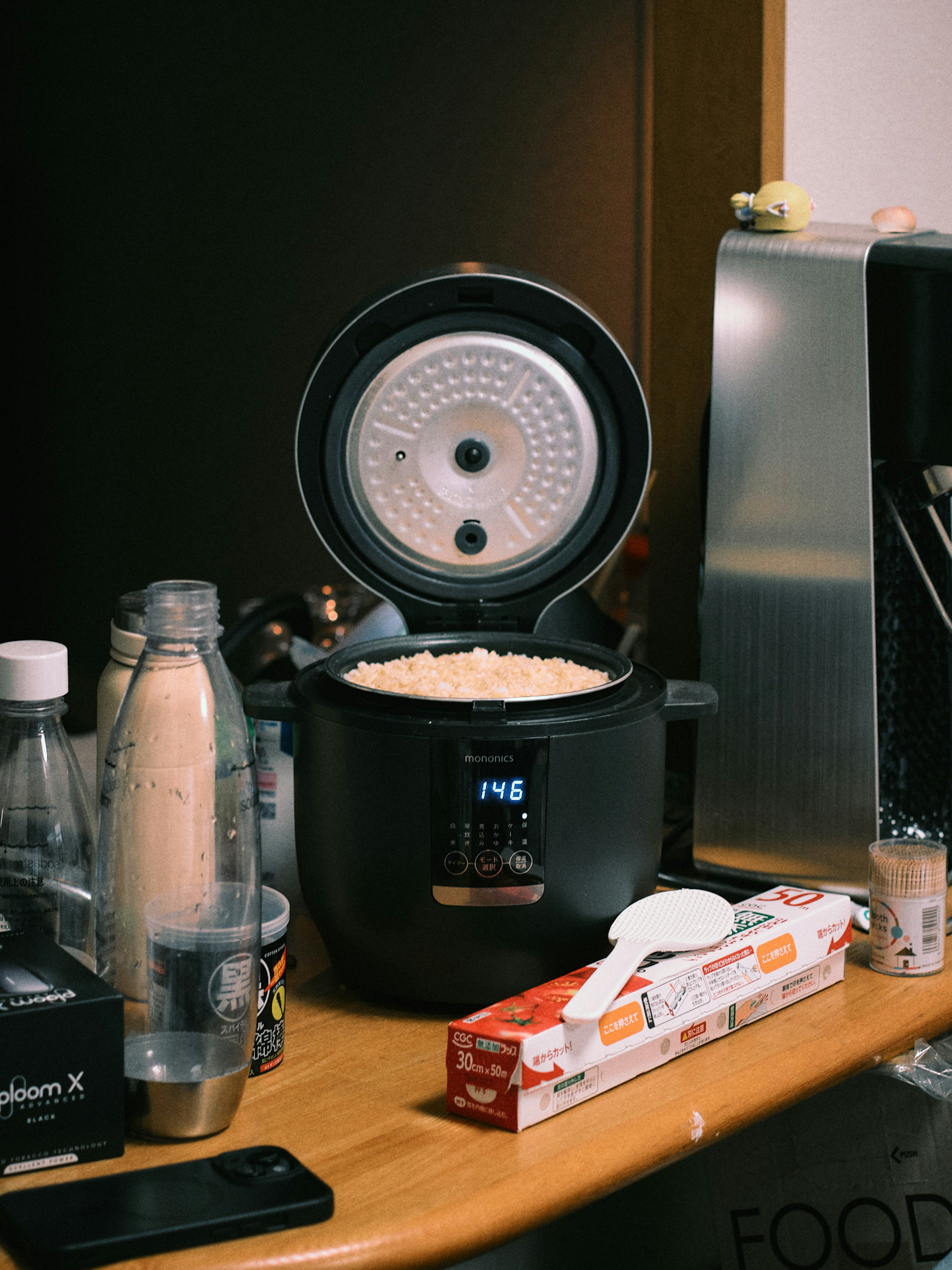 Cuociriso aperto con riso all'interno e oggetti da cucina circostanti