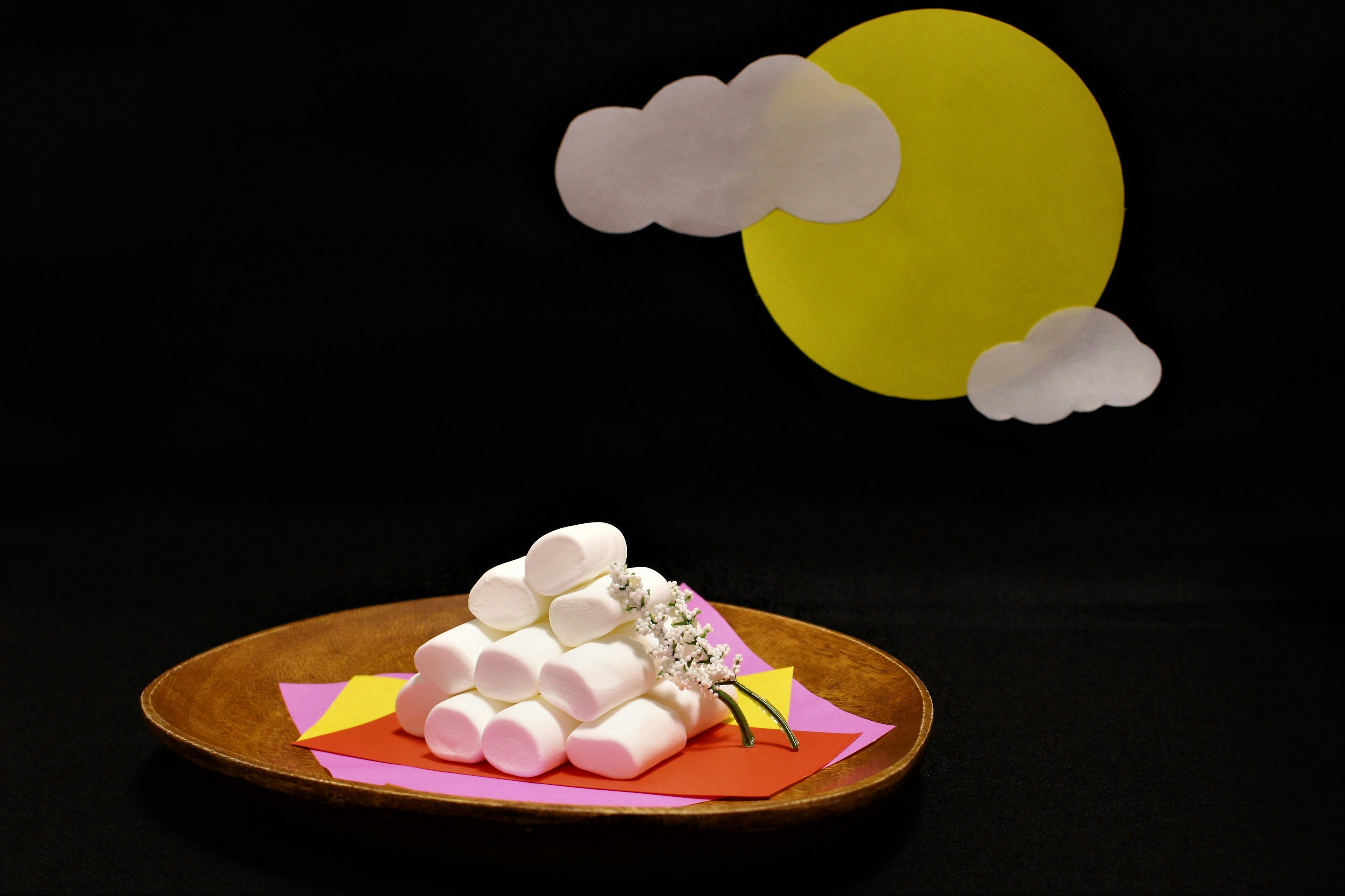 Ein Haufen Marshmallows auf einem Teller mit einer gelben Sonne und weißen Wolken im Hintergrund