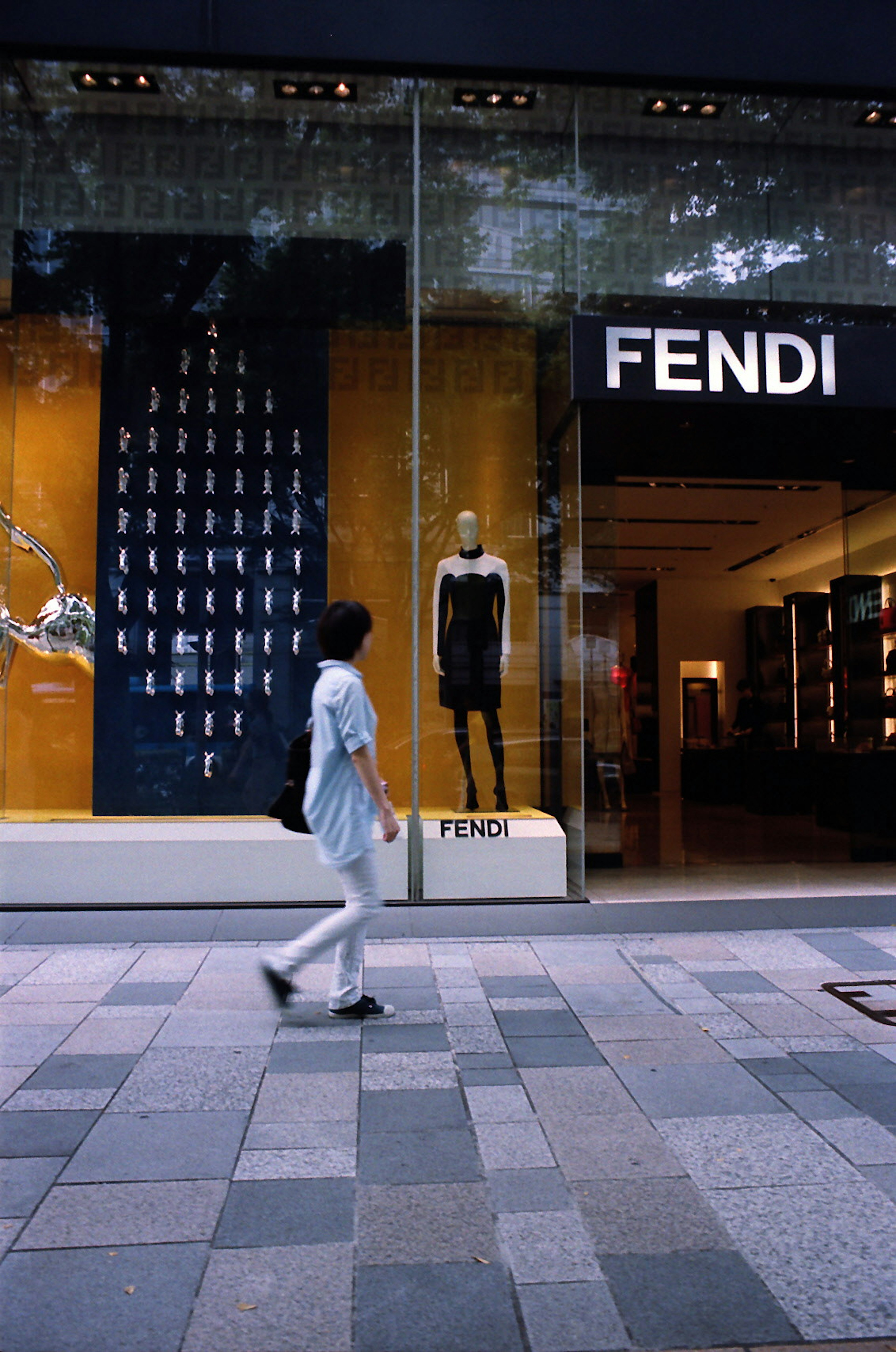 Fendi 매장 앞을 걷는 사람과 진열된 옷이 있는 창