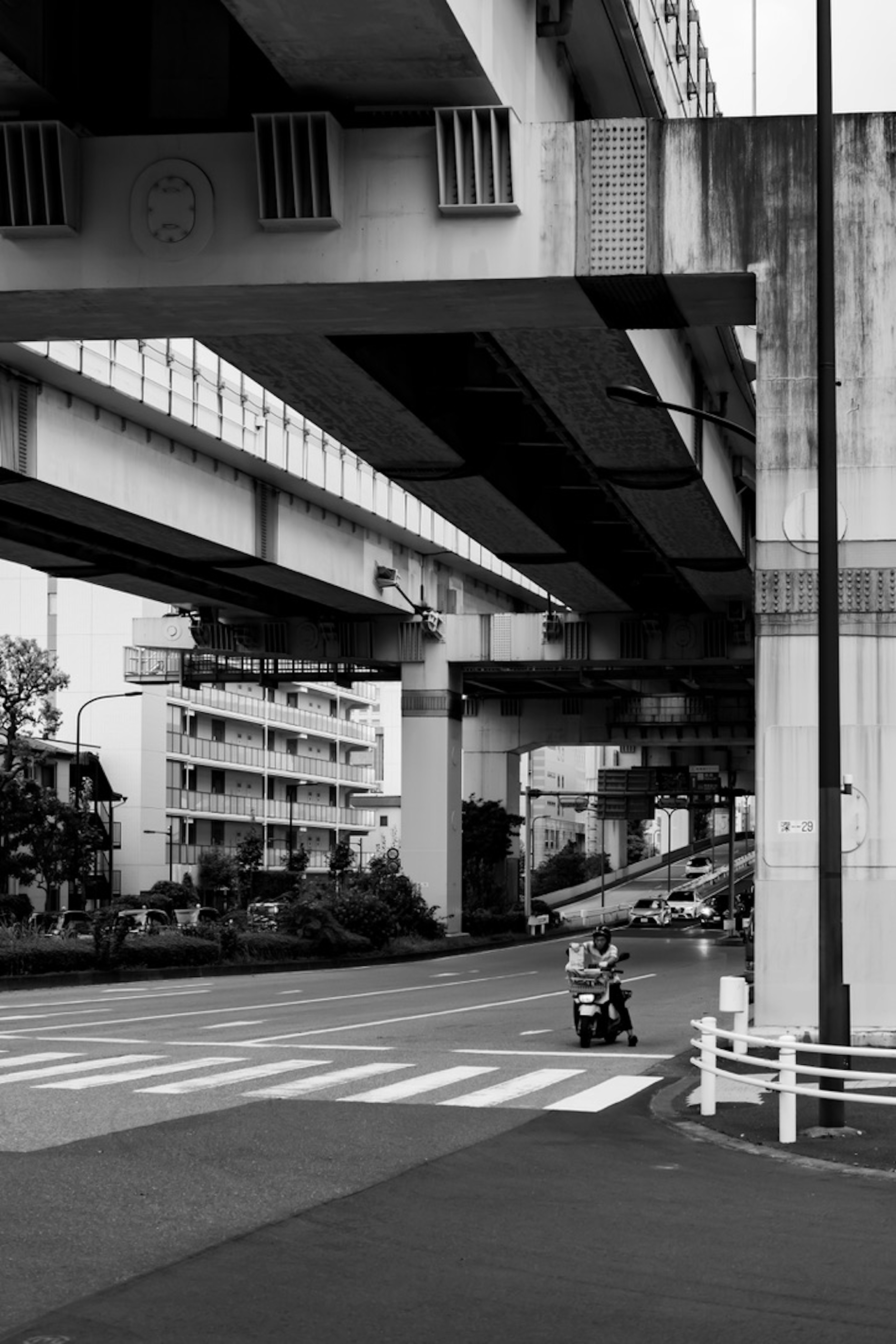 Silhouette of buildings under elevated highway with road