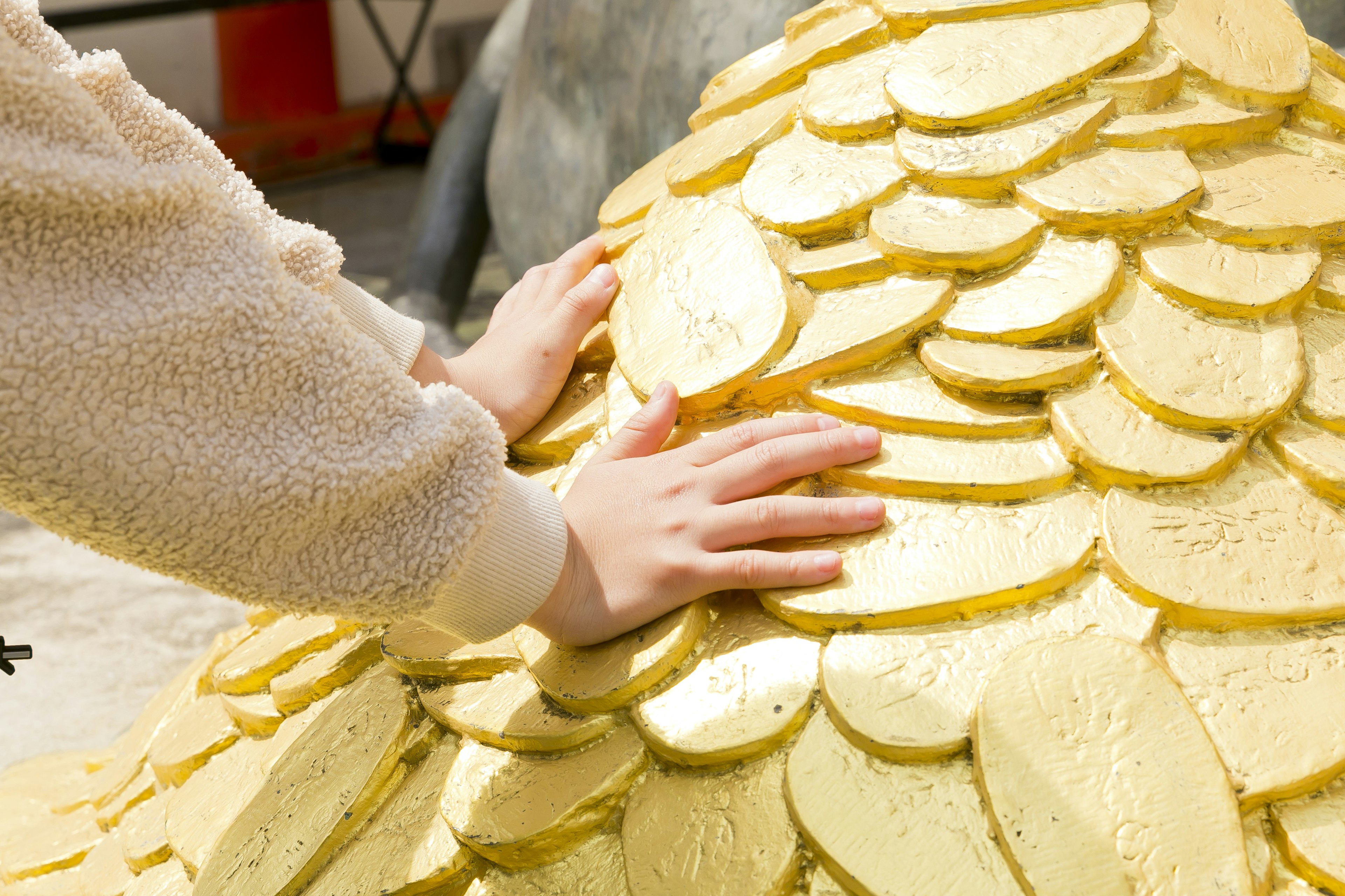 手が金色の鱗に触れている彫刻の一部