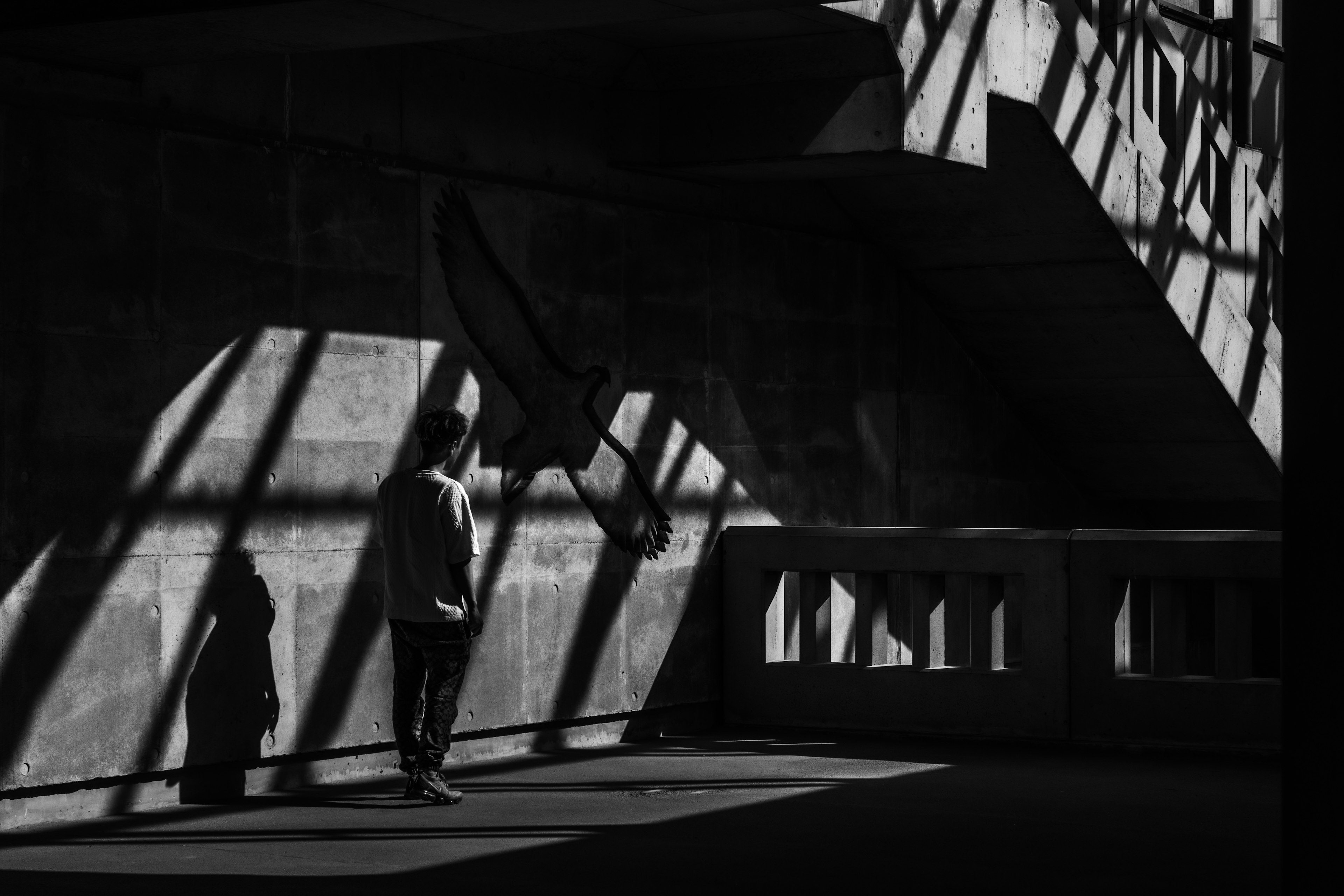 Monochrome image of a person standing in a dark space with intersecting shadows