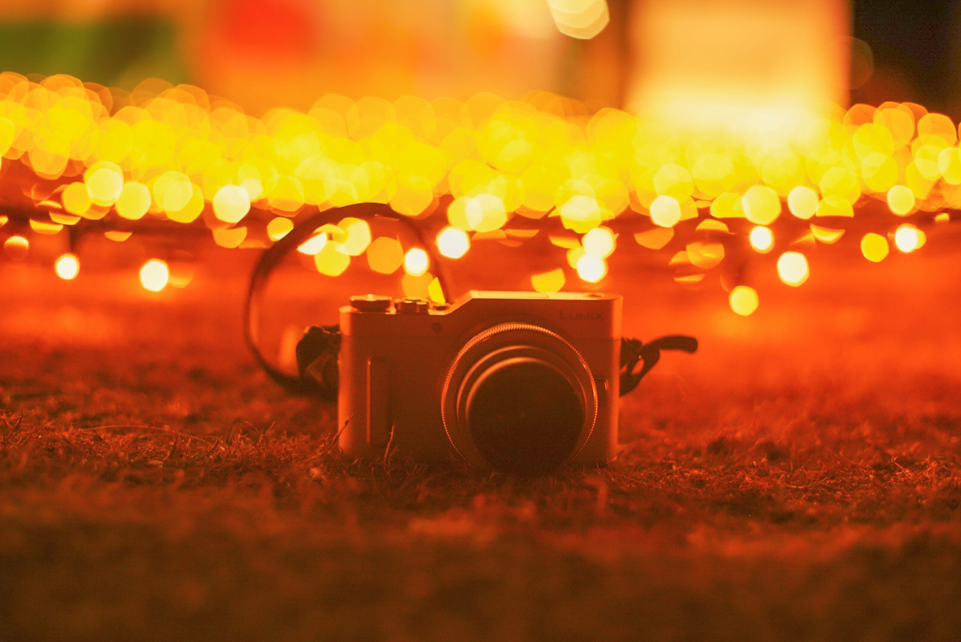 Camera resting on ground with orange lights in background