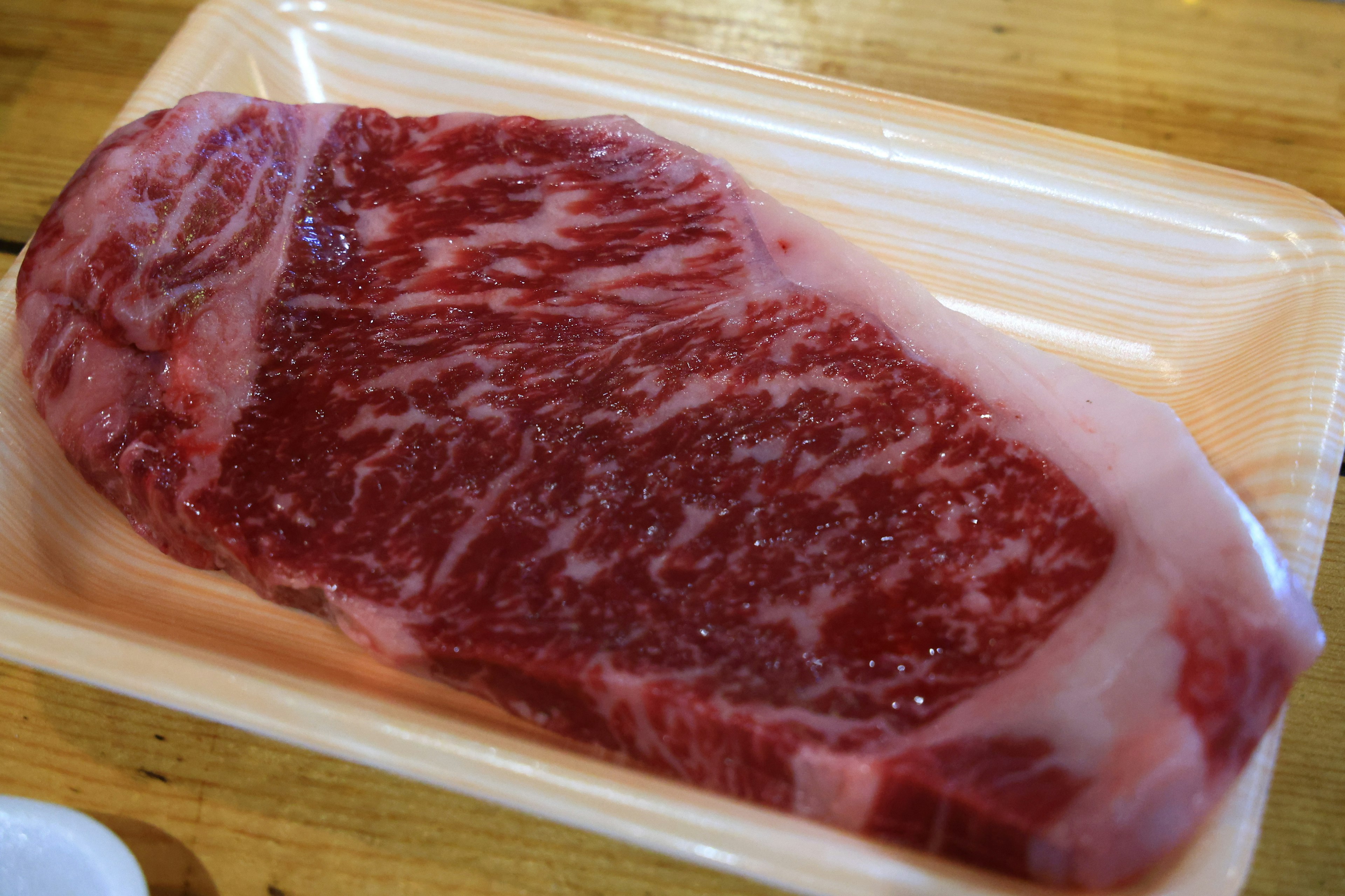 マーブル模様のある生の牛肉のステーキが白いトレイに載っている