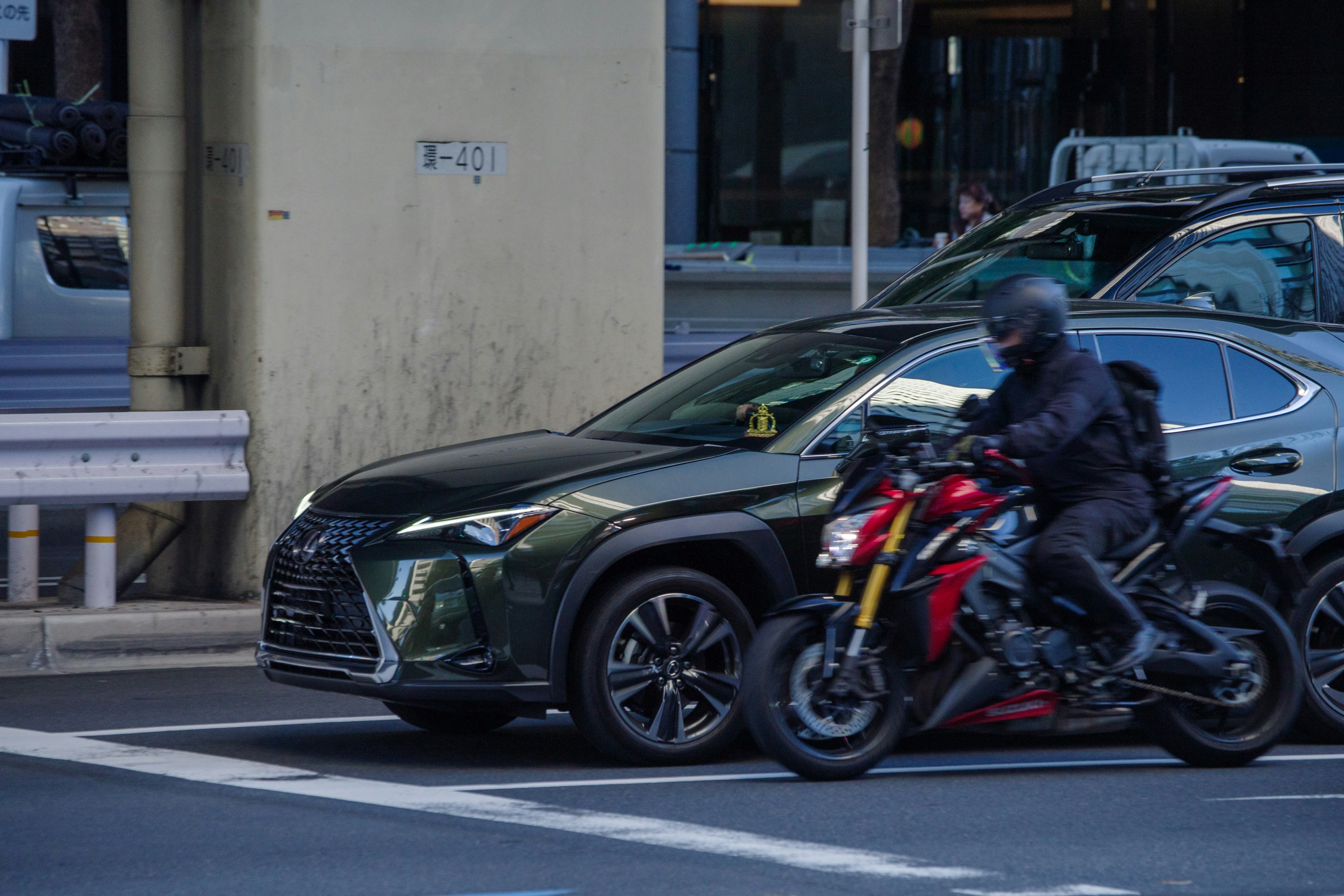 A black SUV and a red motorcycle at an intersection in an urban setting