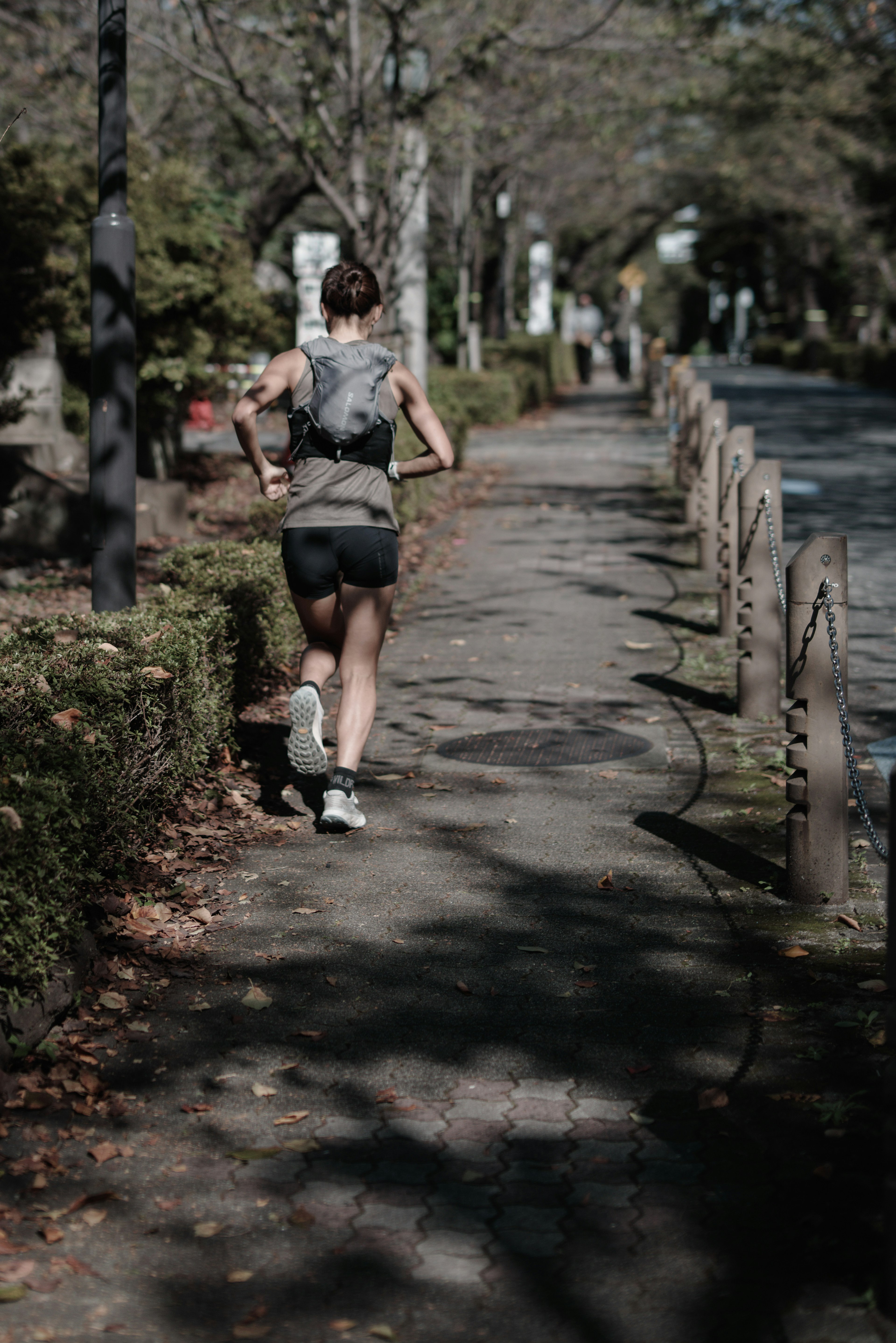 Femme courant sur un chemin de parc entouré de feuilles d'automne