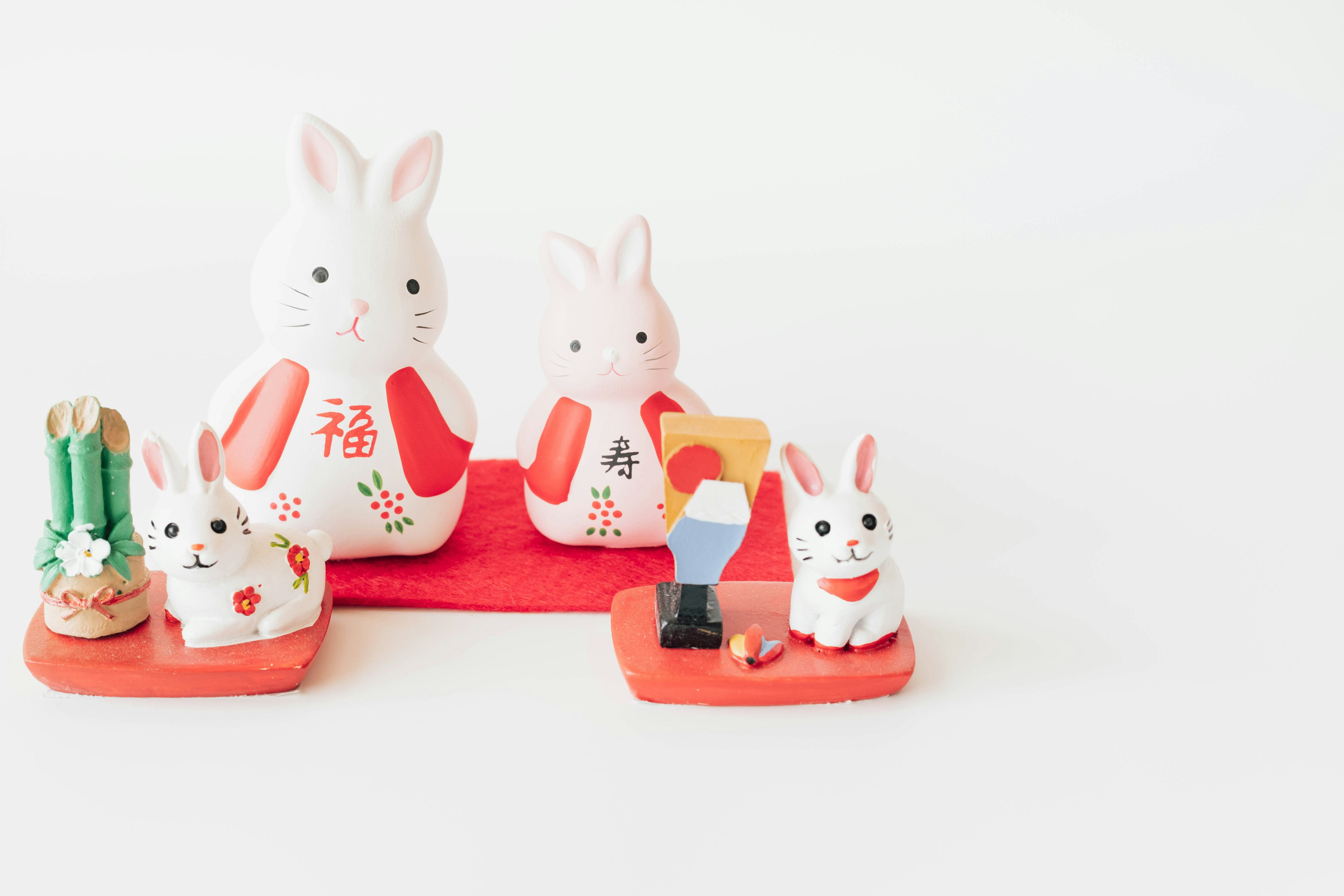 Decorative white and red rabbit figurines arranged on a light background