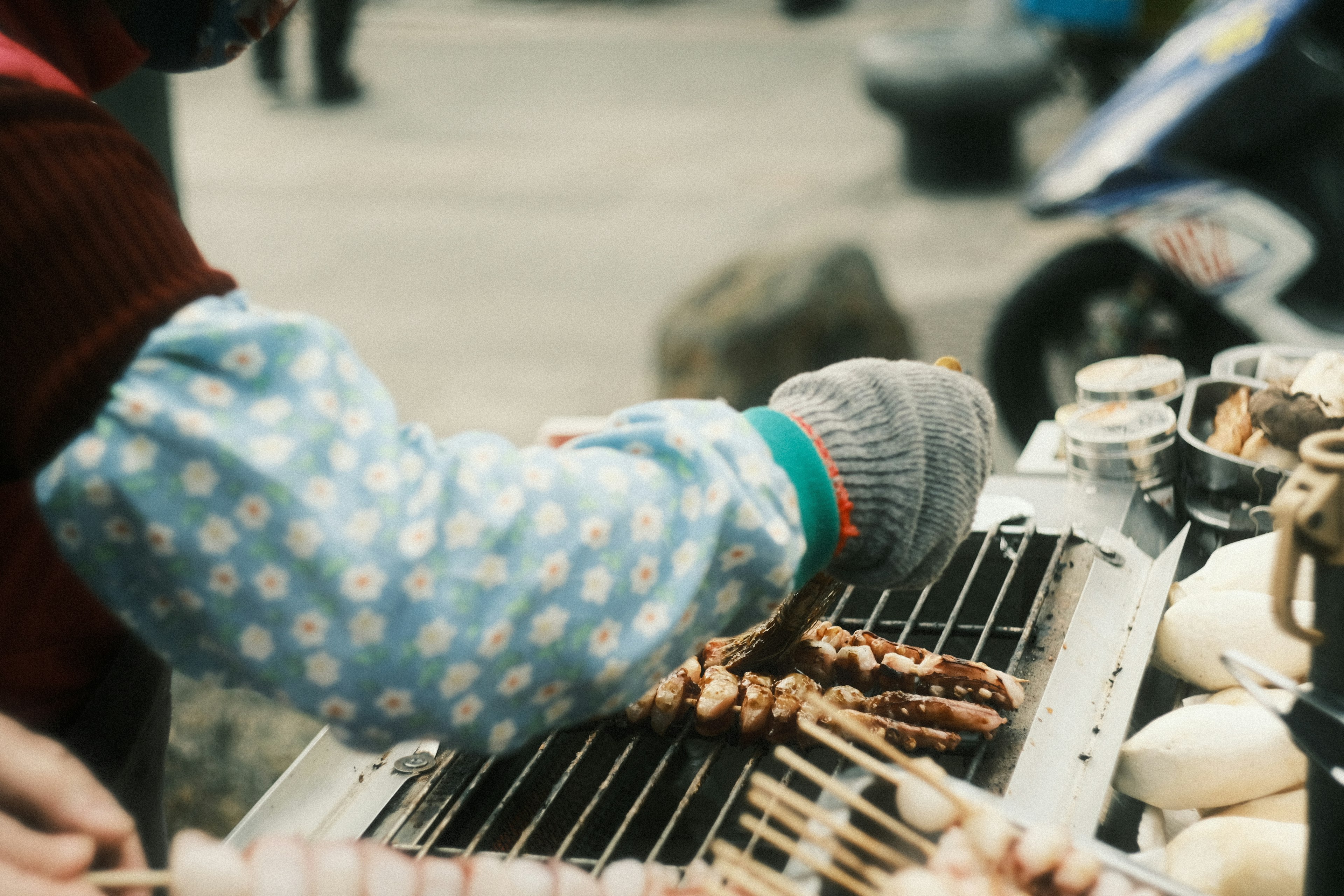 屋台で串焼きを調理している手