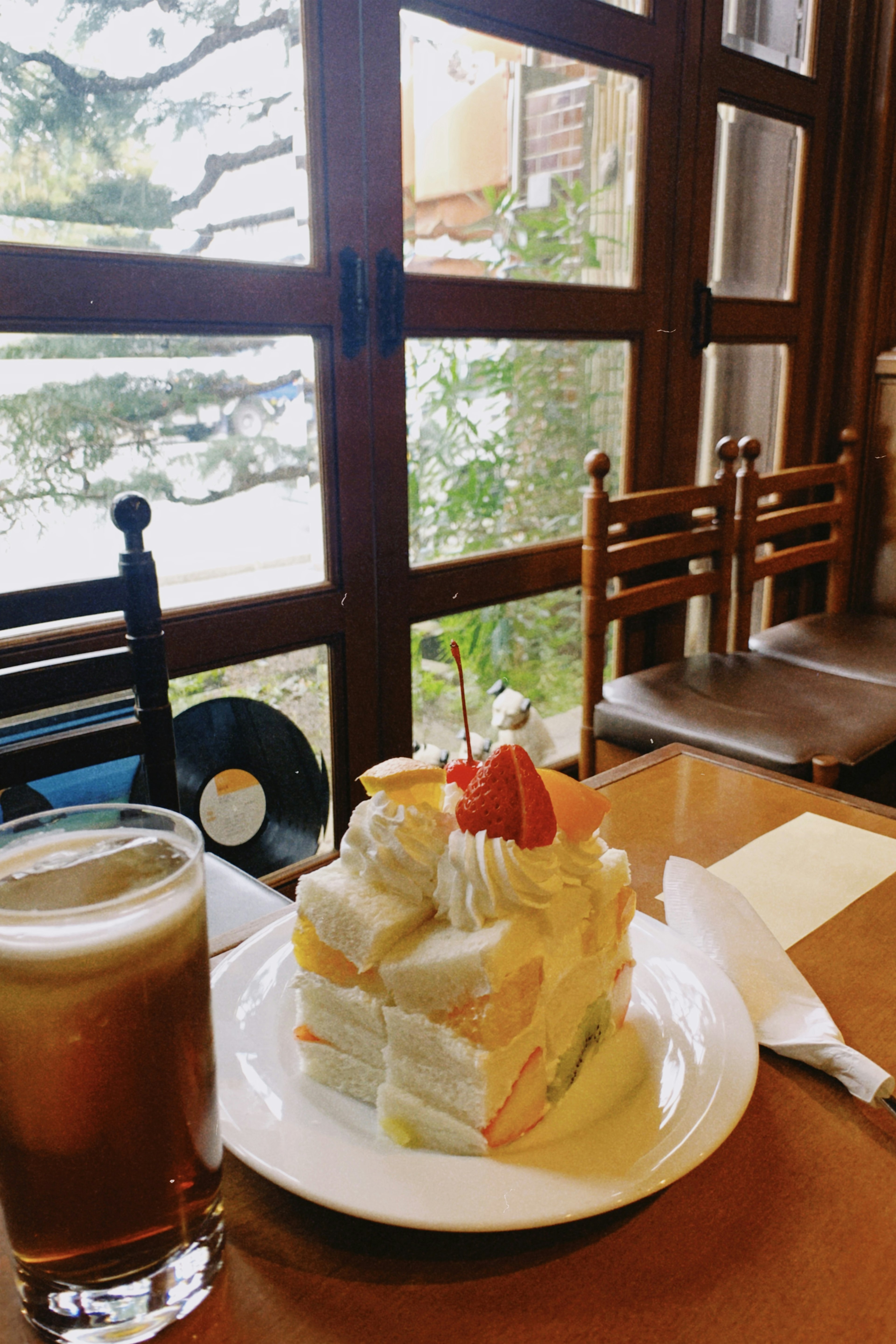 Un gâteau aux fruits et une boisson sur une table de café avec une vue sur la verdure à l'extérieur