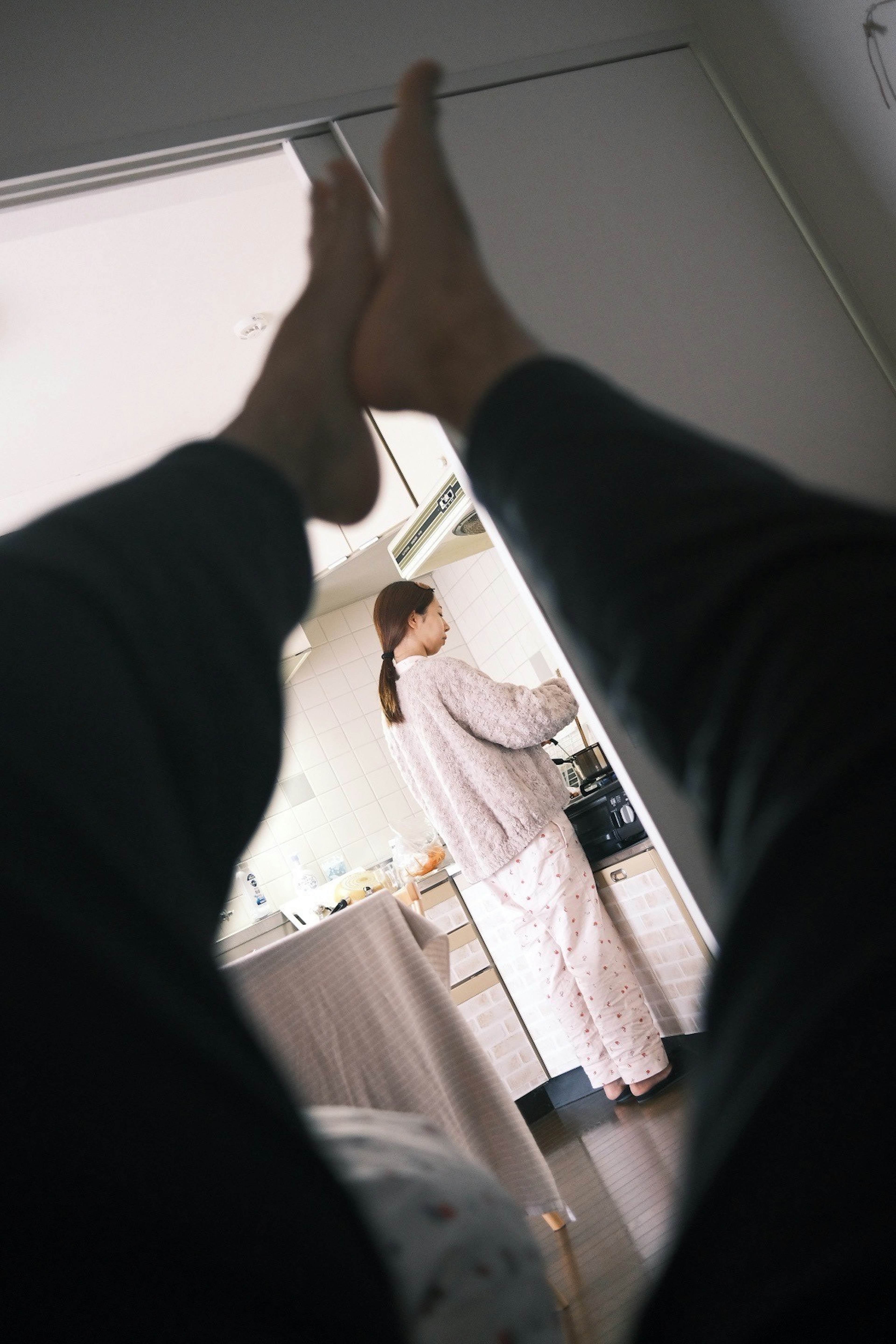 Vista dal letto che mostra i piedi e una donna che cucina in cucina