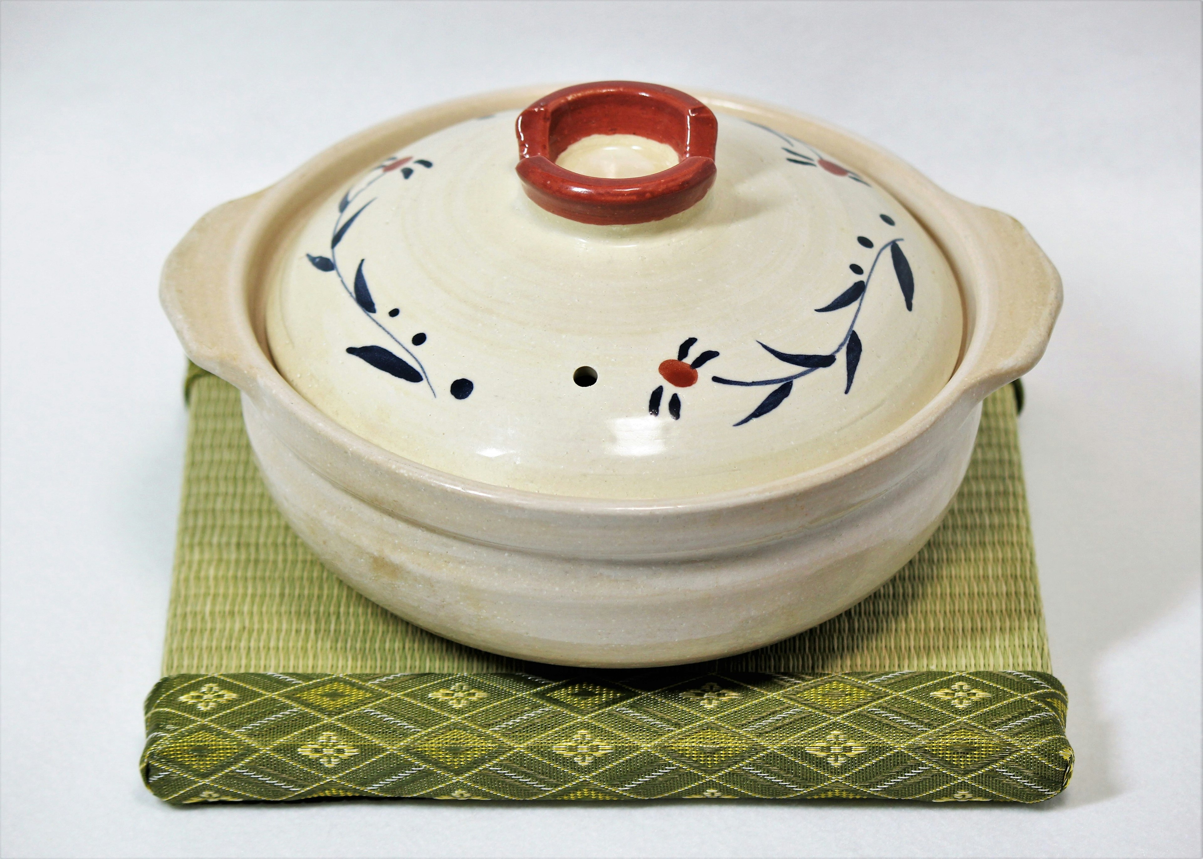 A beautifully designed ceramic pot placed on a green mat