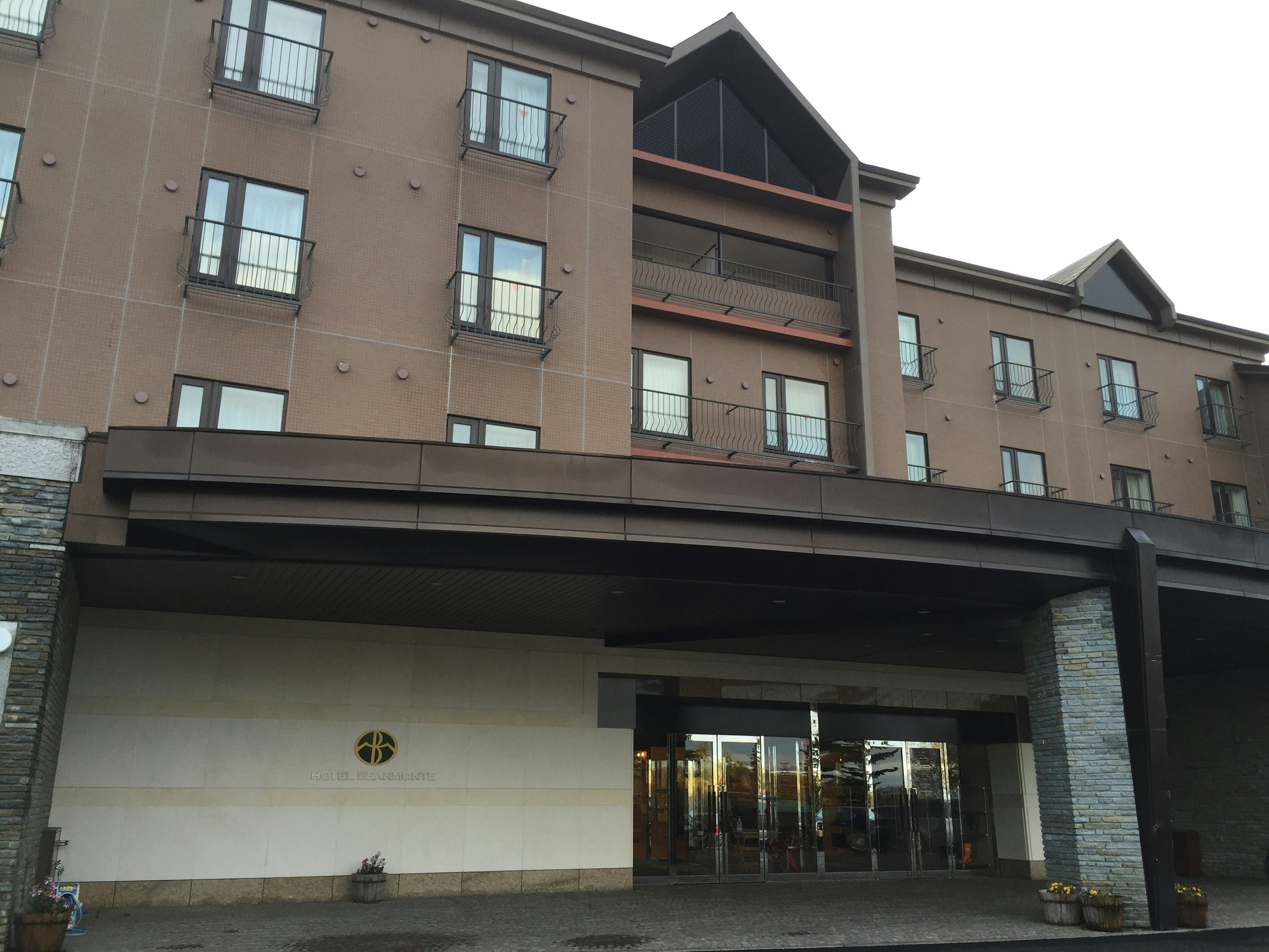 Four-story hotel with brown exterior featuring large windows and entrance