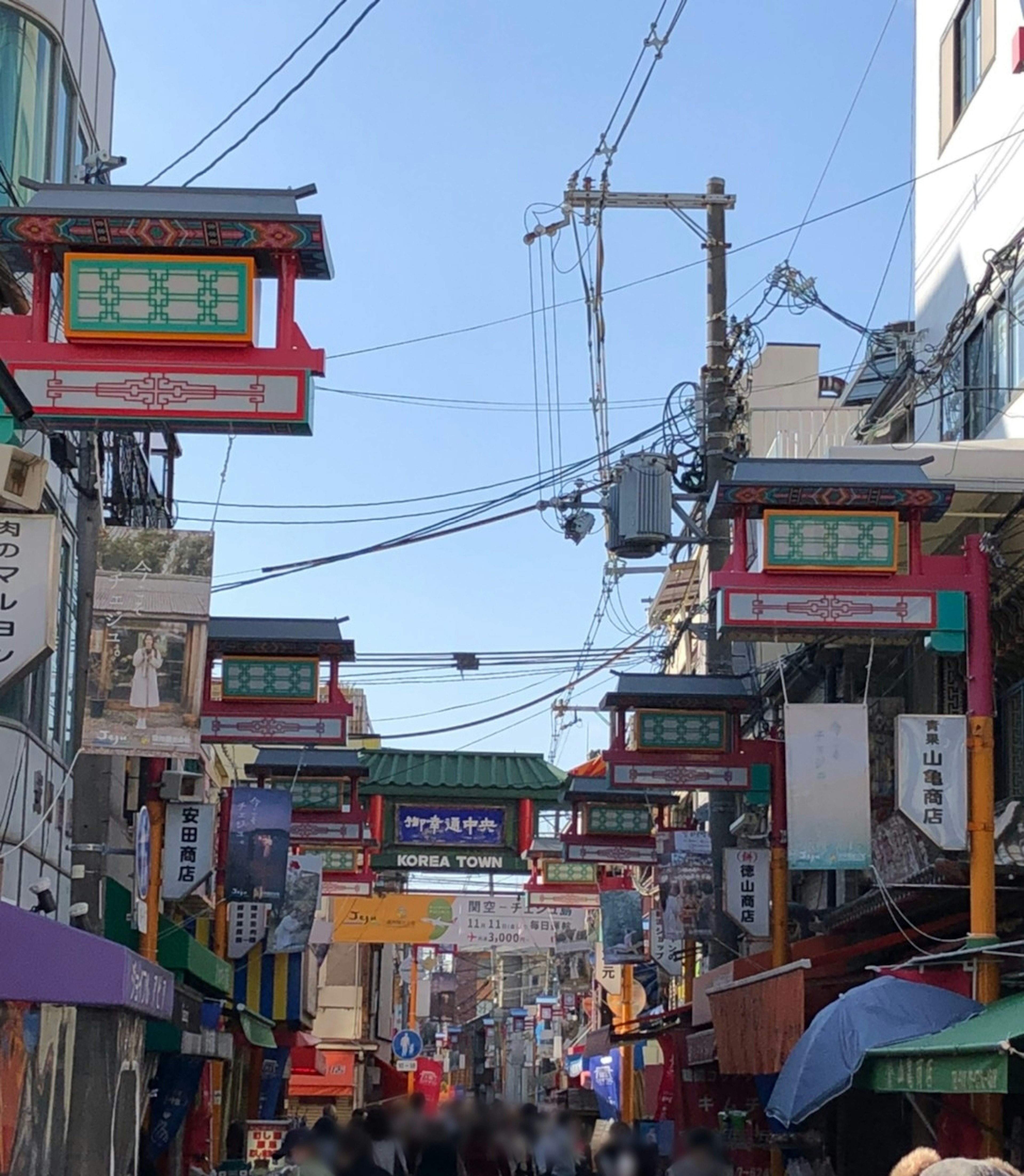 Busy street in Chinatown featuring red archway signs and power lines