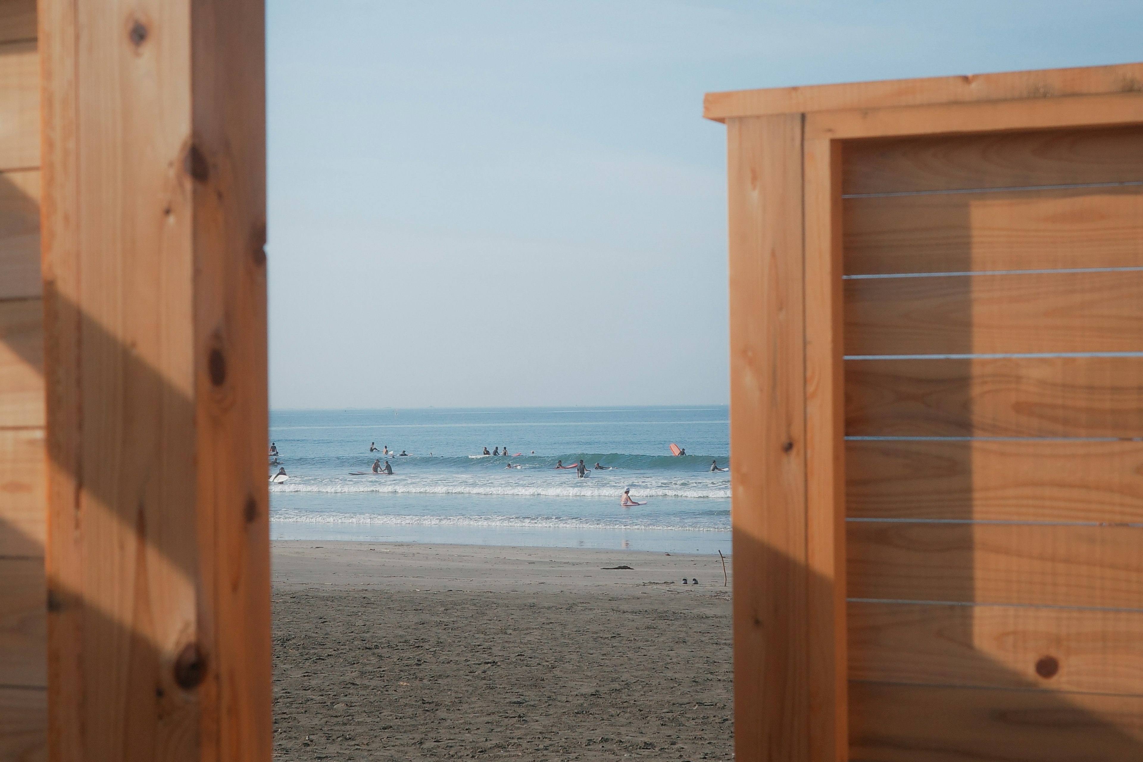 Vue de l'océan et de la plage de sable à travers une clôture en bois