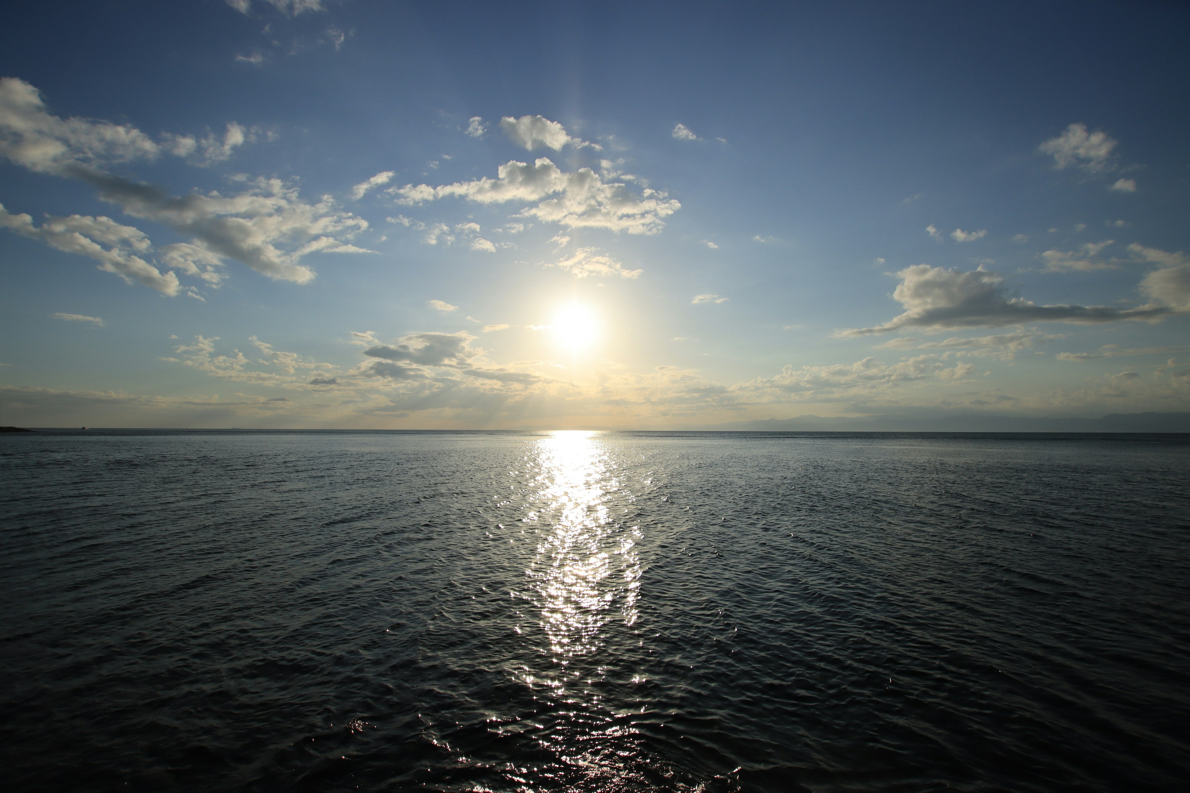 A scenic view of the ocean with the sun setting in the background