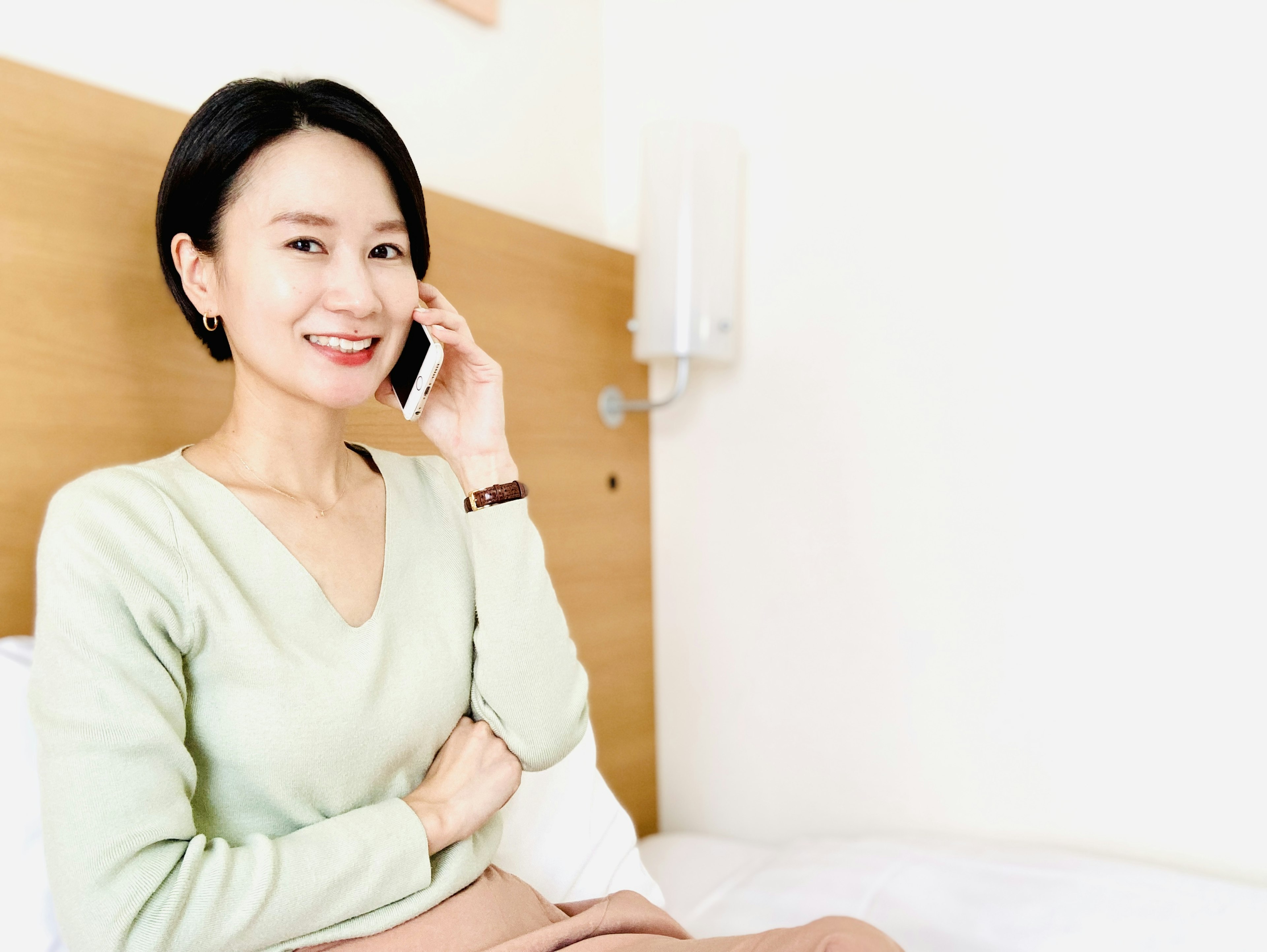 Femme souriante parlant au téléphone dans une chambre confortable