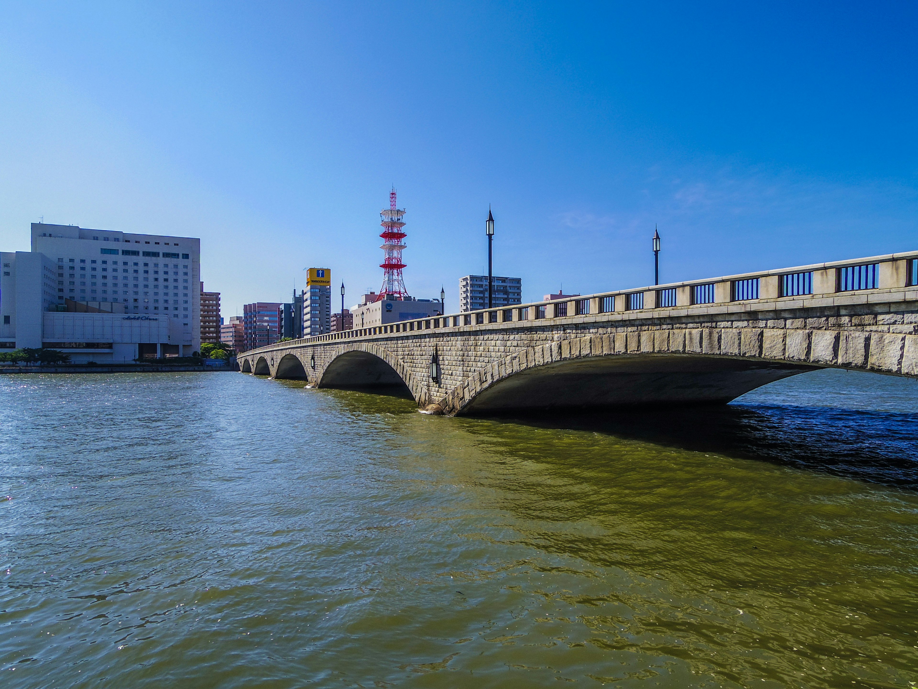 Pont en pierre sur une rivière sous un ciel bleu