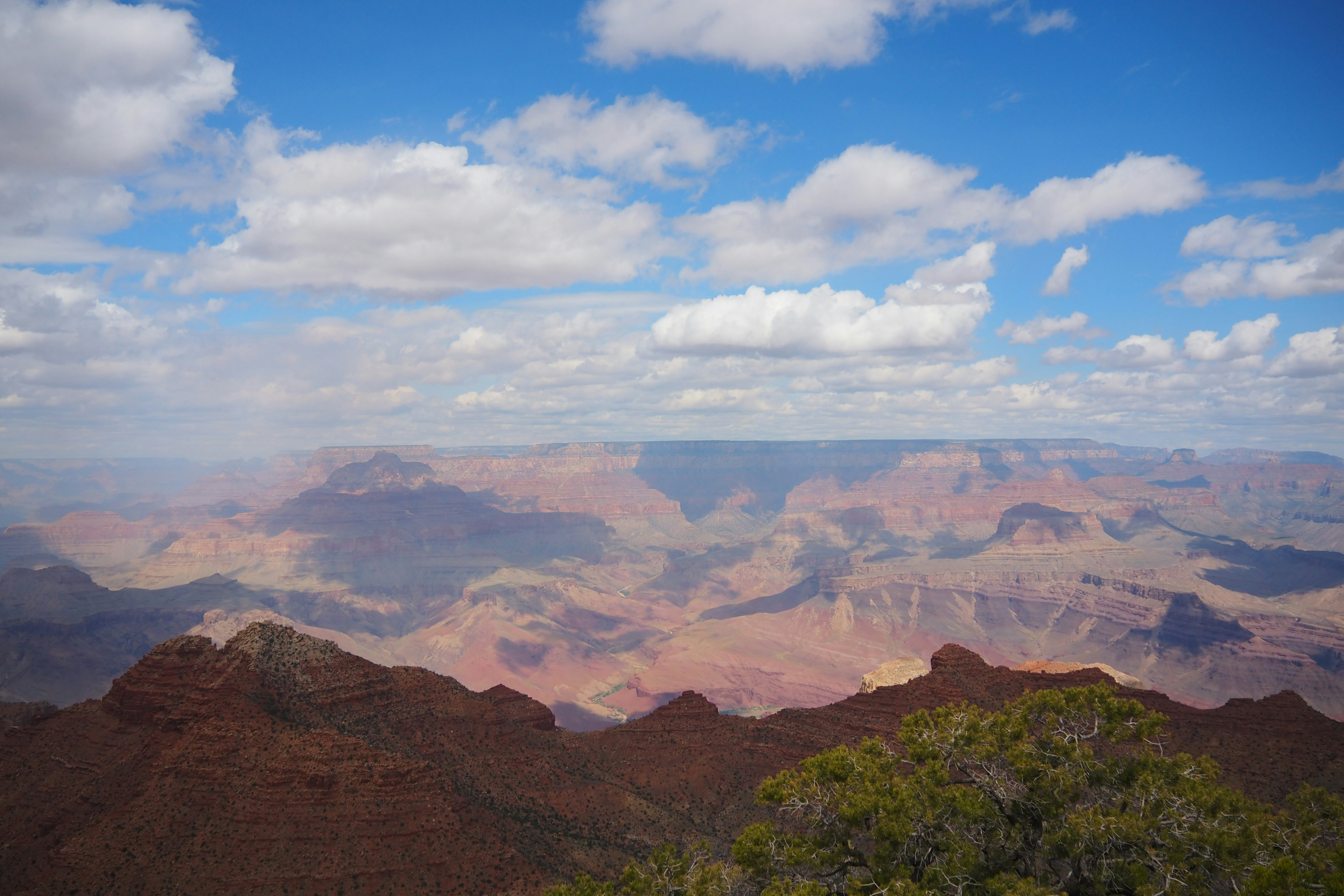 Khung cảnh rộng lớn của Grand Canyon với bầu trời xanh và mây