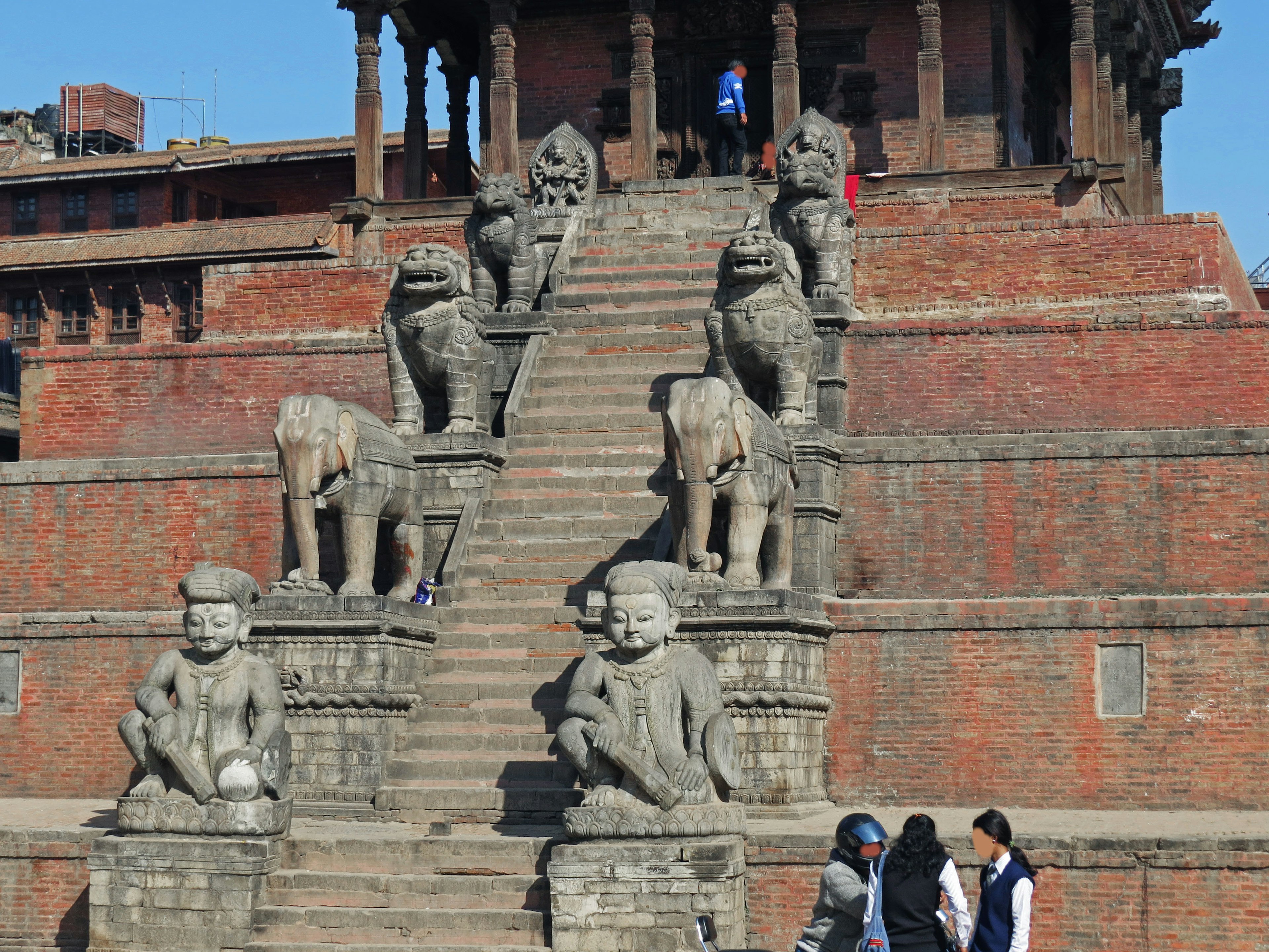 Statues en pierre sur les marches d'un ancien temple avec des visiteurs