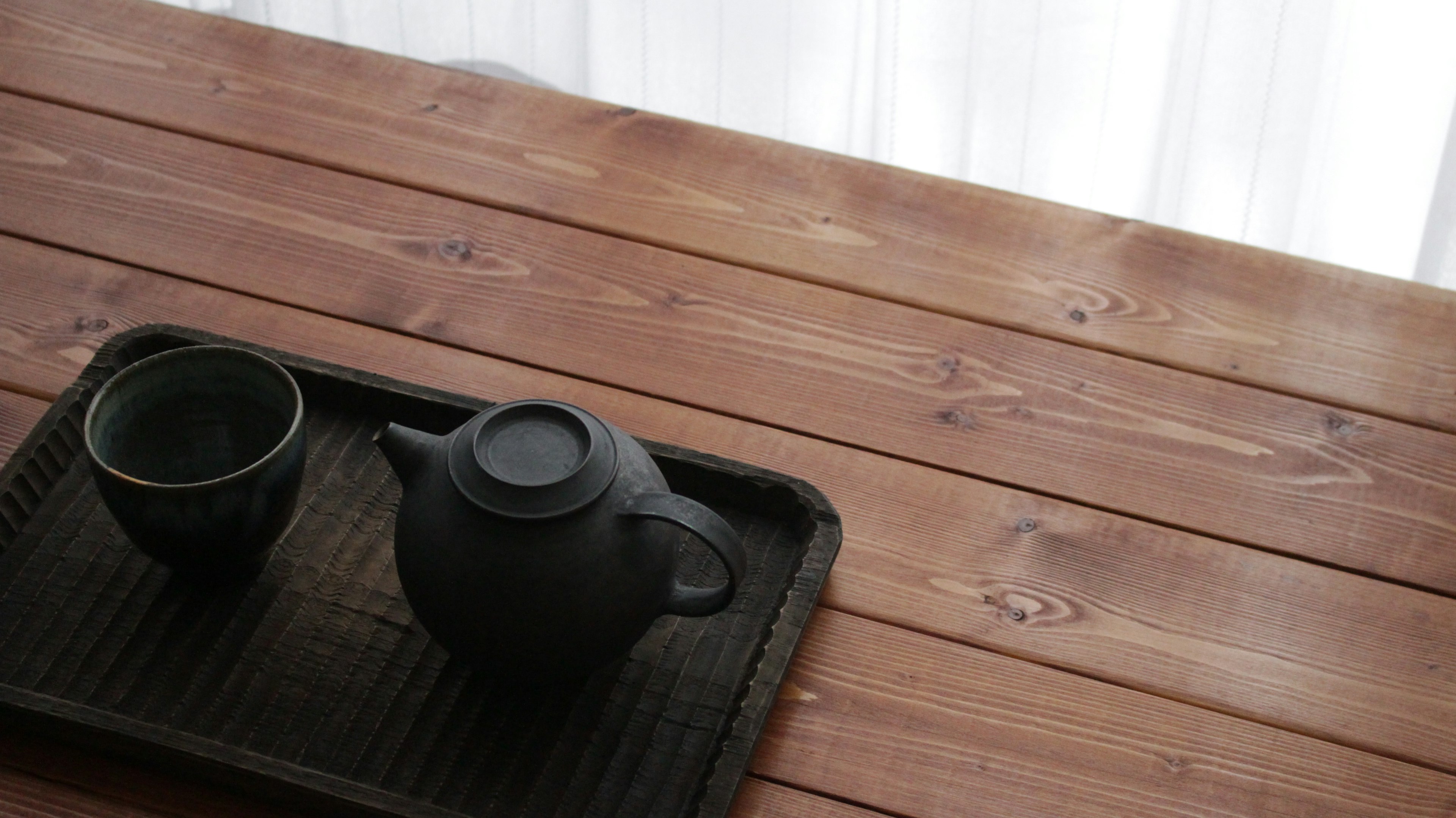 Black teapot and cup set on a wooden table