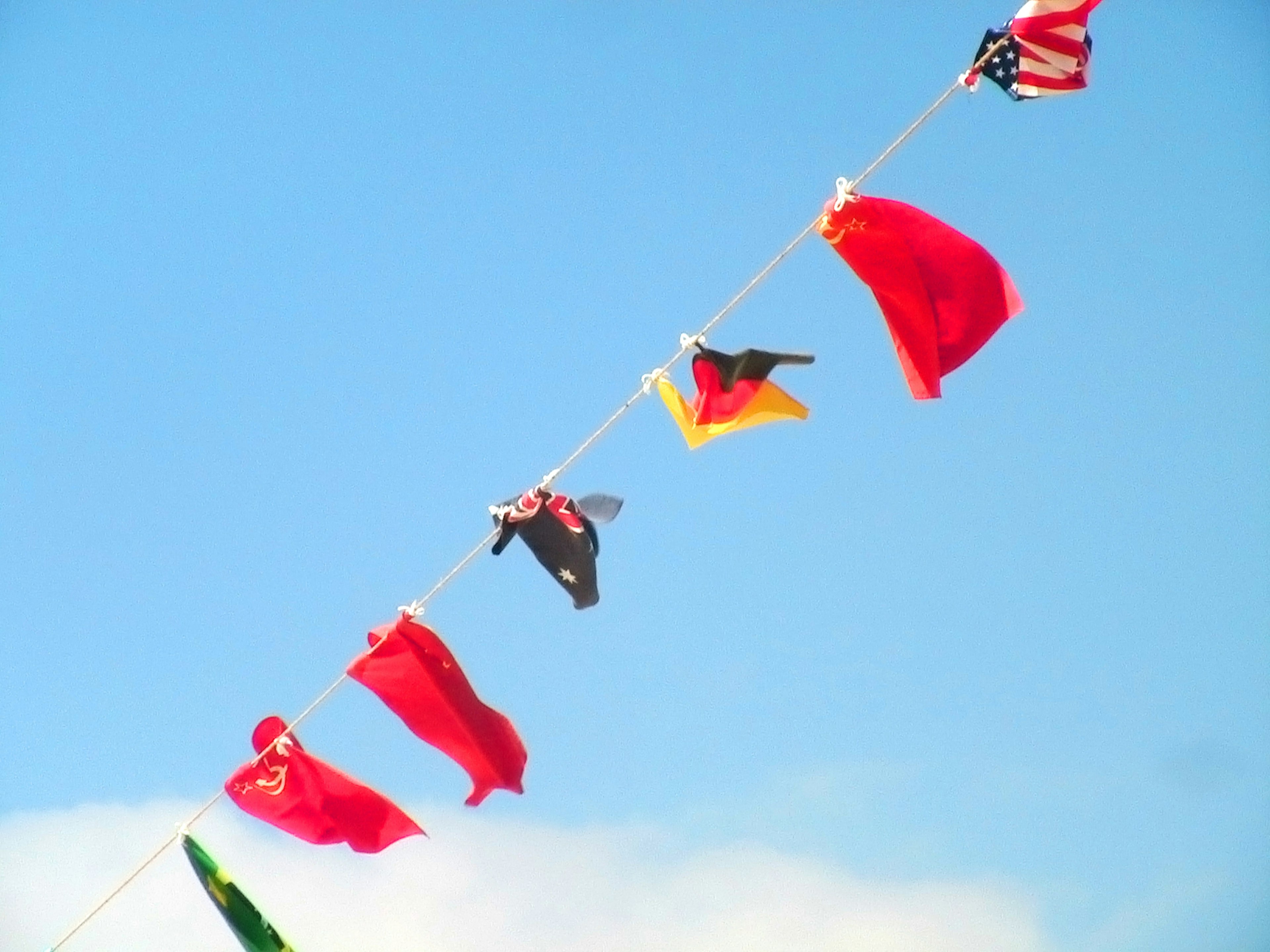 Bendera internasional berwarna-warni tergantung di bawah langit biru