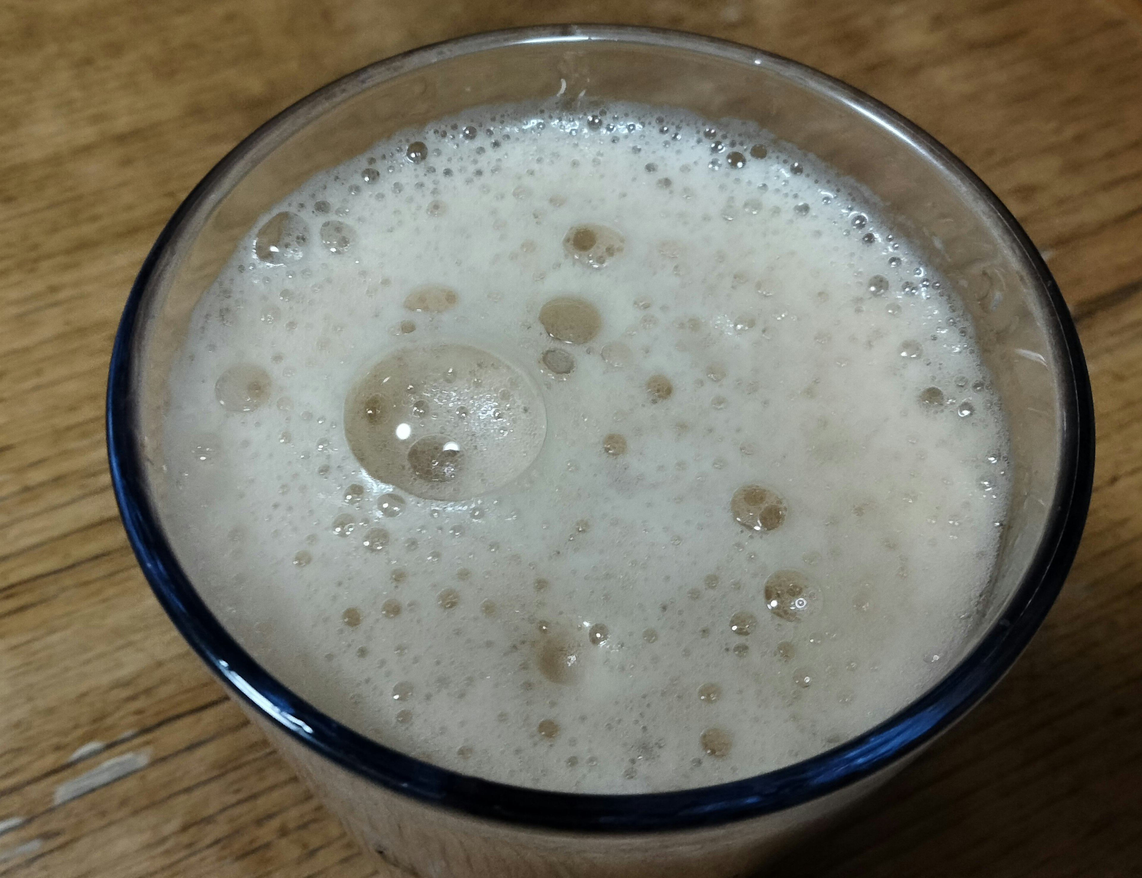 A frothy cream-colored beverage in a clear glass